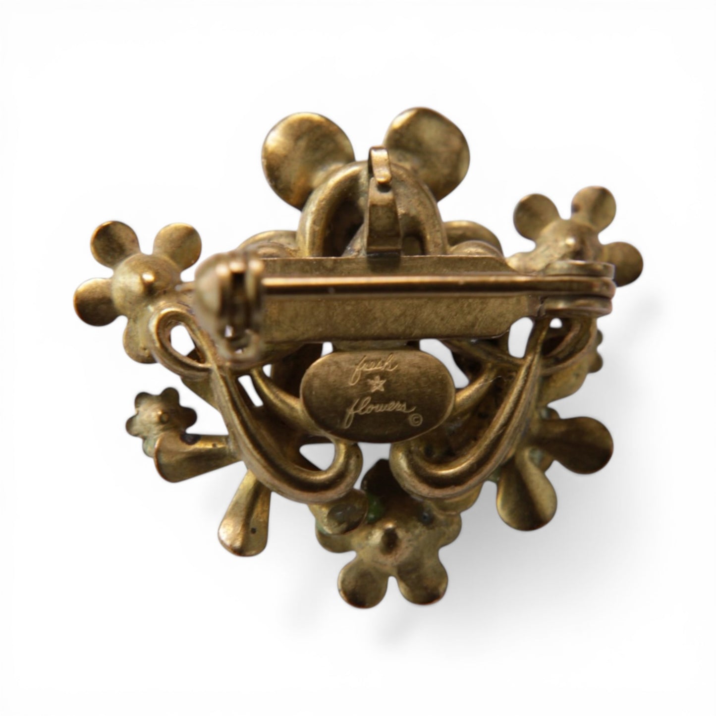 Reverse of cluster brooch showing antiqued brass scroll and loop backing, roll-over C-catch clasp, and oval fresh flowers ...