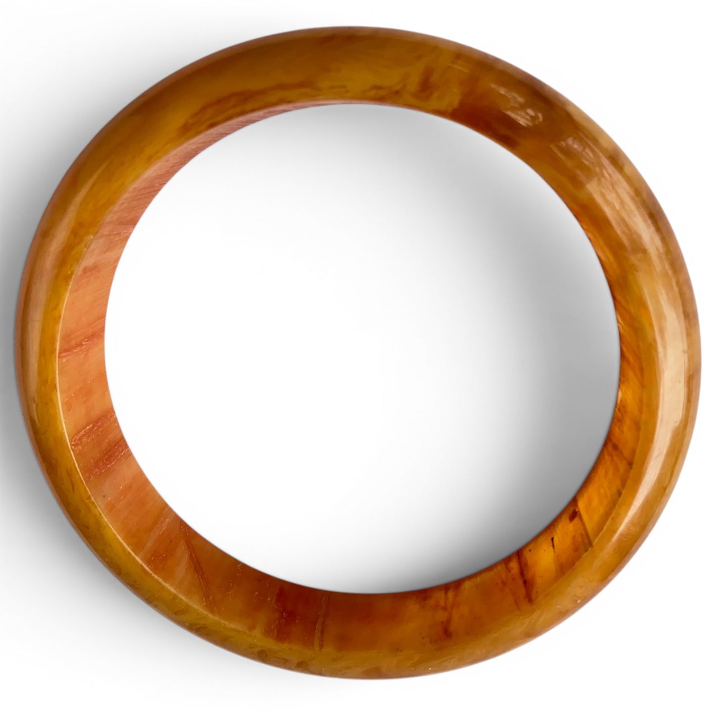 Close-up of Bakelite bangle surface showing natural mottling, amber-to-orange coloration, and largely intact high-shine po...