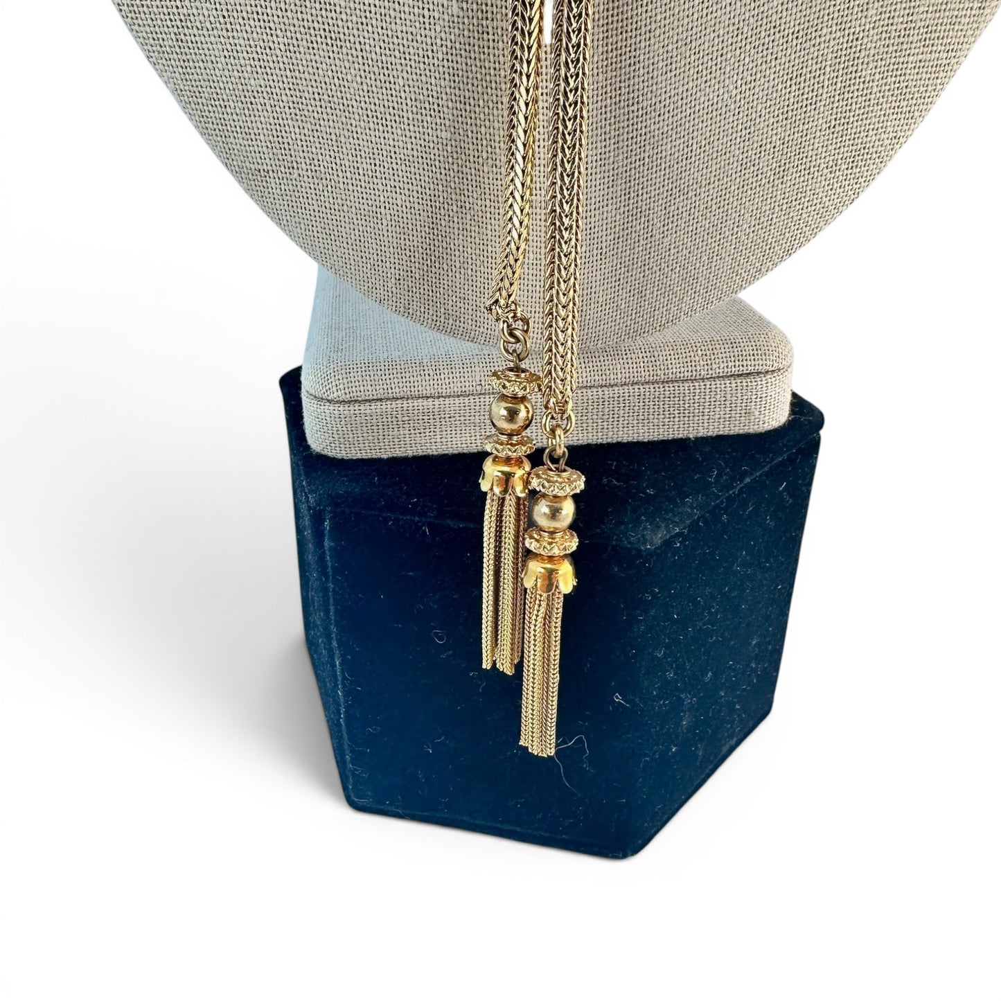 Full-length view of gold-tone lariat necklace with four hanging chain tassel pendants below the sliding center piece