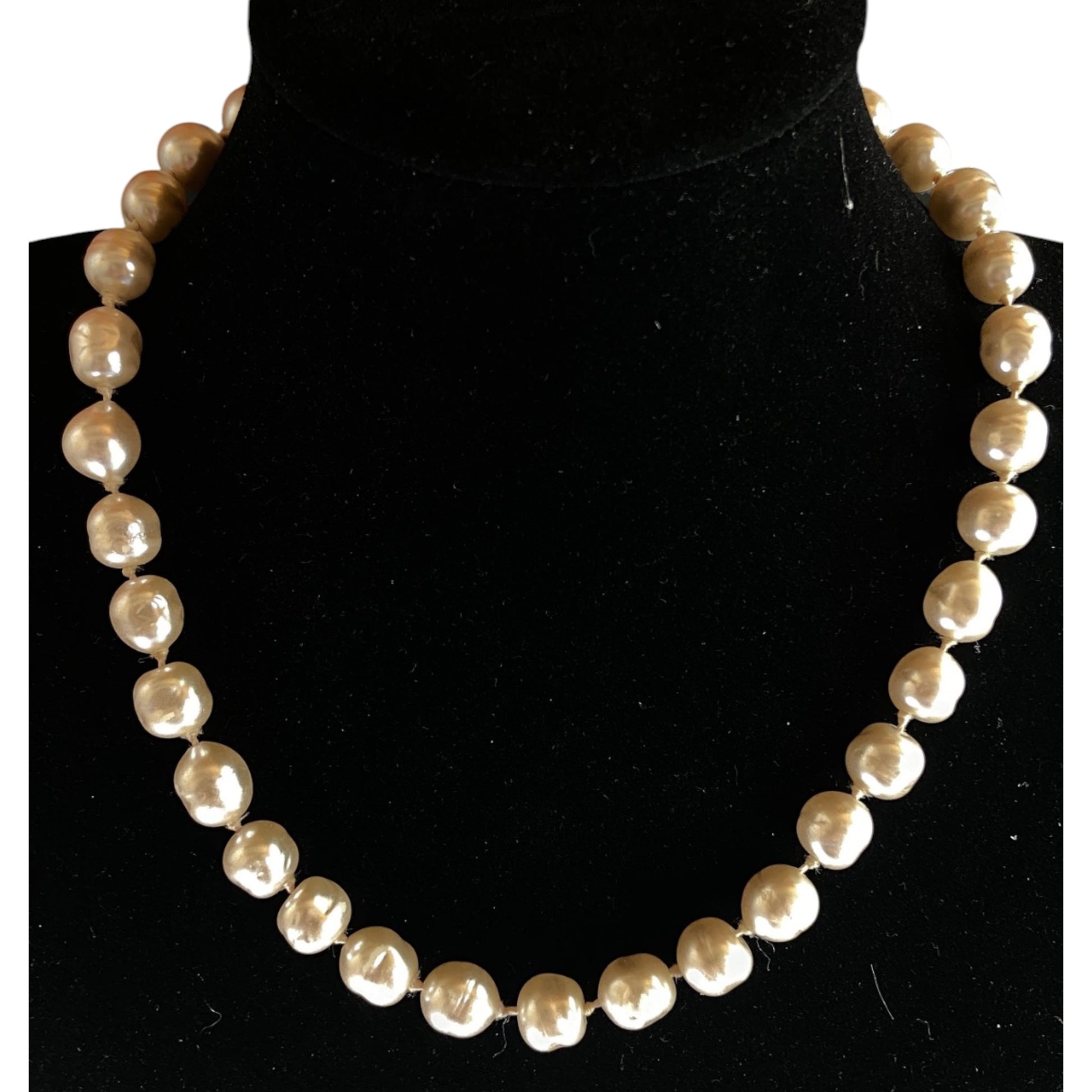 Full-length view of a single-strand baroque pearl necklace, warm cream and champagne tones, natural light
