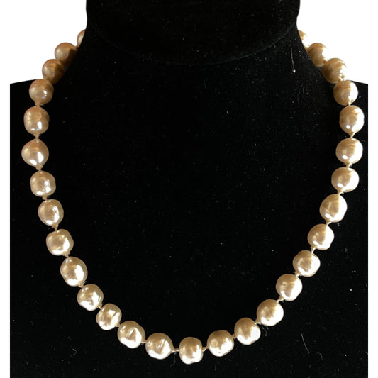 Full-length view of a single-strand baroque pearl necklace, warm cream and champagne tones, natural light