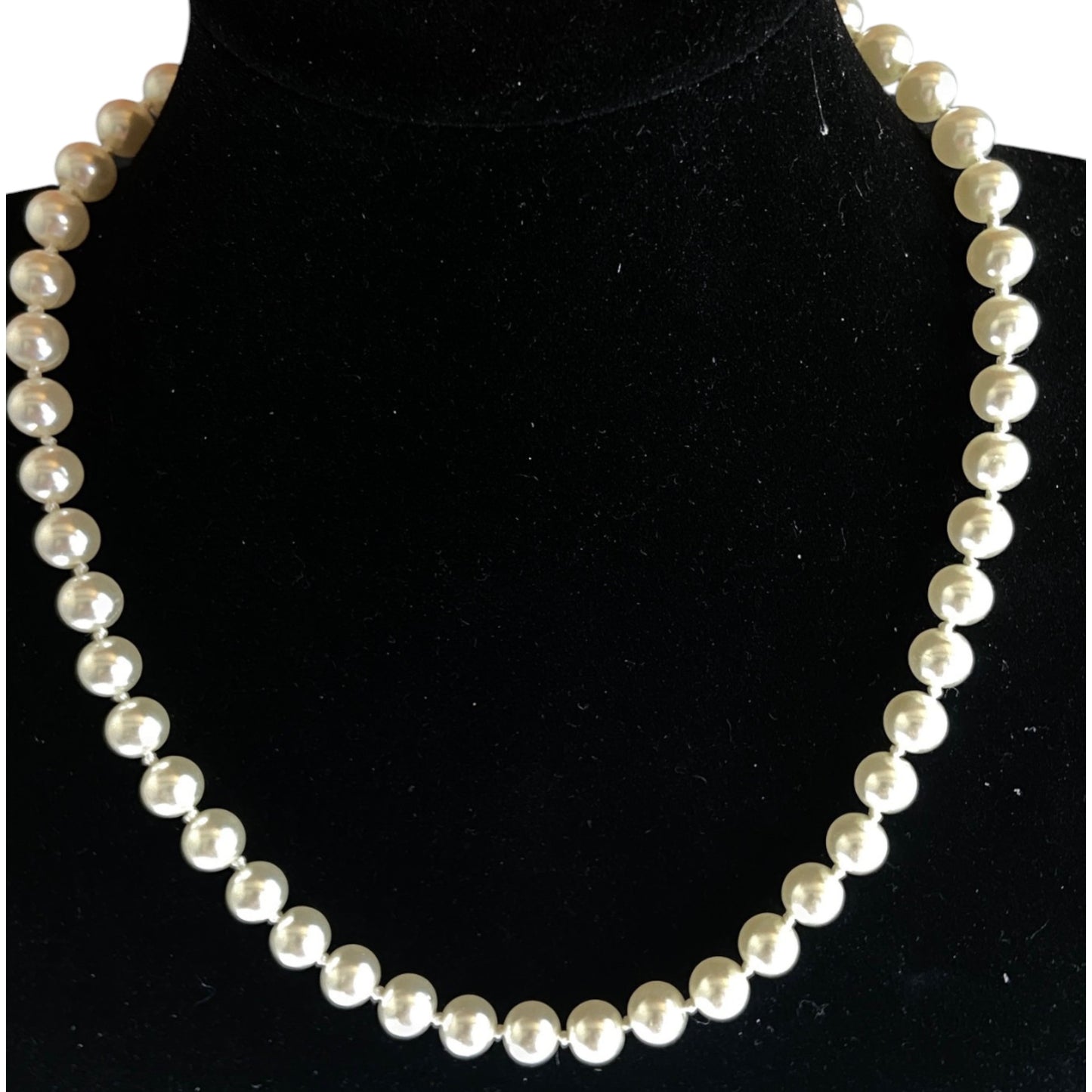Single-strand cream-white faux pearl necklace with hand-knotting displayed on a black velvet bust form