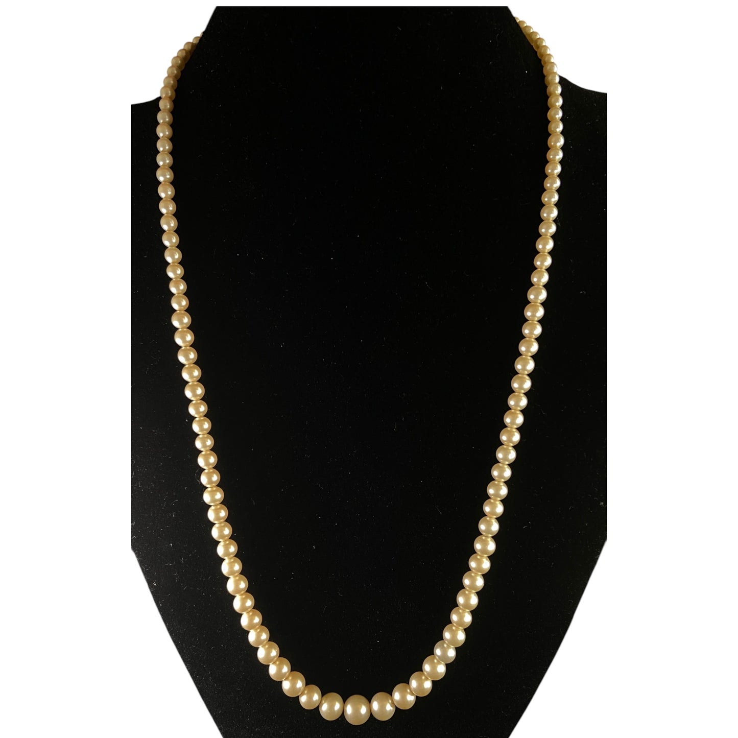 Graduated single-strand cream faux pearl necklace with gold-tone diamond-shaped box clasp, full length view on white backg...