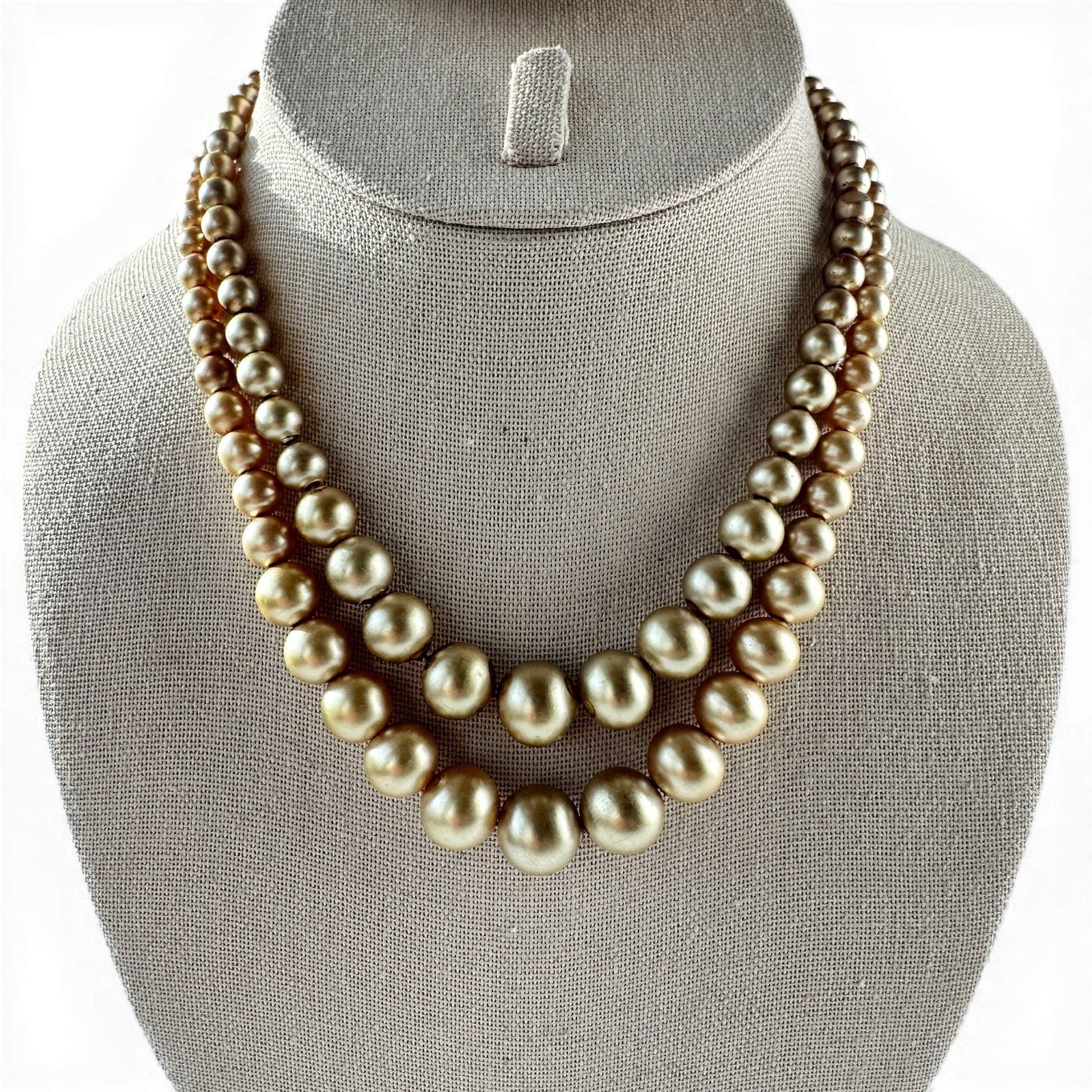 Double-strand graduated golden-bronze faux pearl choker necklace with knotted cord stringing, laid flat on white surface