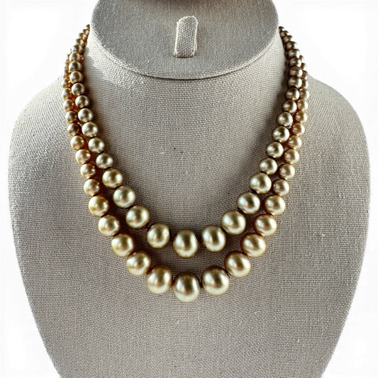 Double-strand graduated golden-bronze faux pearl choker necklace with knotted cord stringing, laid flat on white surface