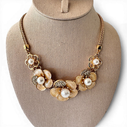 Gold-tone floral bib necklace with three cream champagne enamel flowers and faux pearl centers on double-strand chain