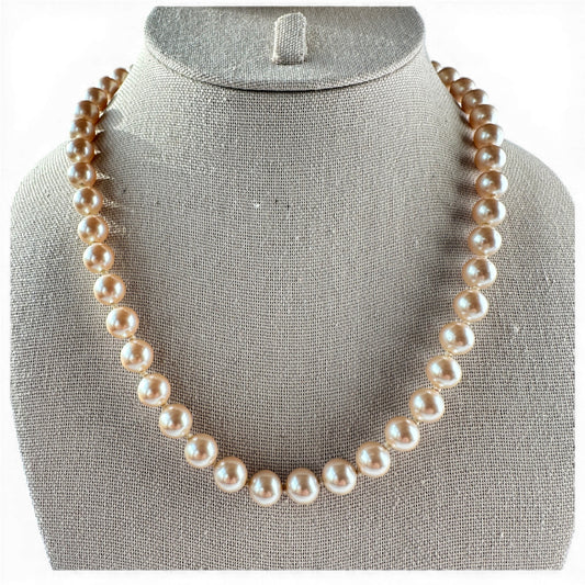 Single-strand champagne faux pearl necklace with hand-knotted cord, laid flat on neutral surface, full length view