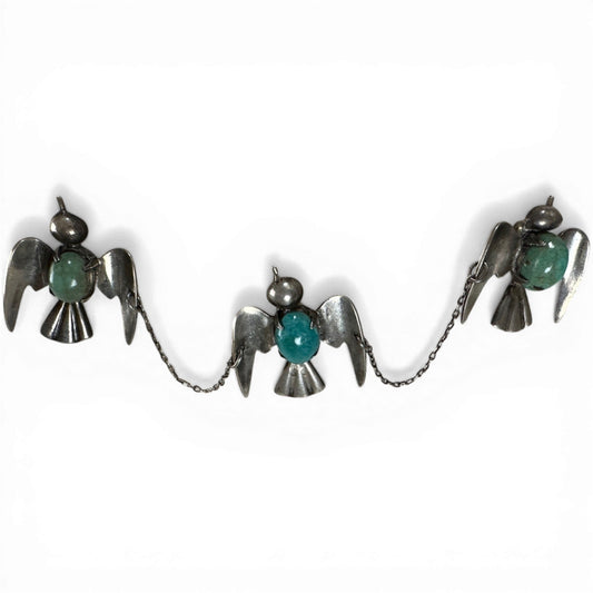 Three linked sterling silver bird brooches with bezel-set turquoise cabochons and fine rolo chain connections, front view