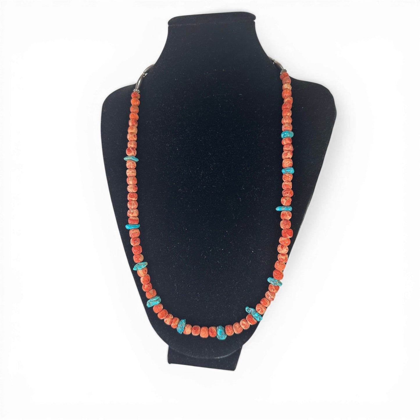 Close-up of elongated hollow oval silver beads and small round silver spacers at the center front of the necklace