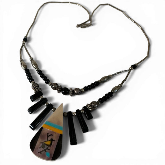 Close-up of channel inlay teardrop pendant with geometric diagonal banding in turquoise, black, cream, and yellow-gold stones