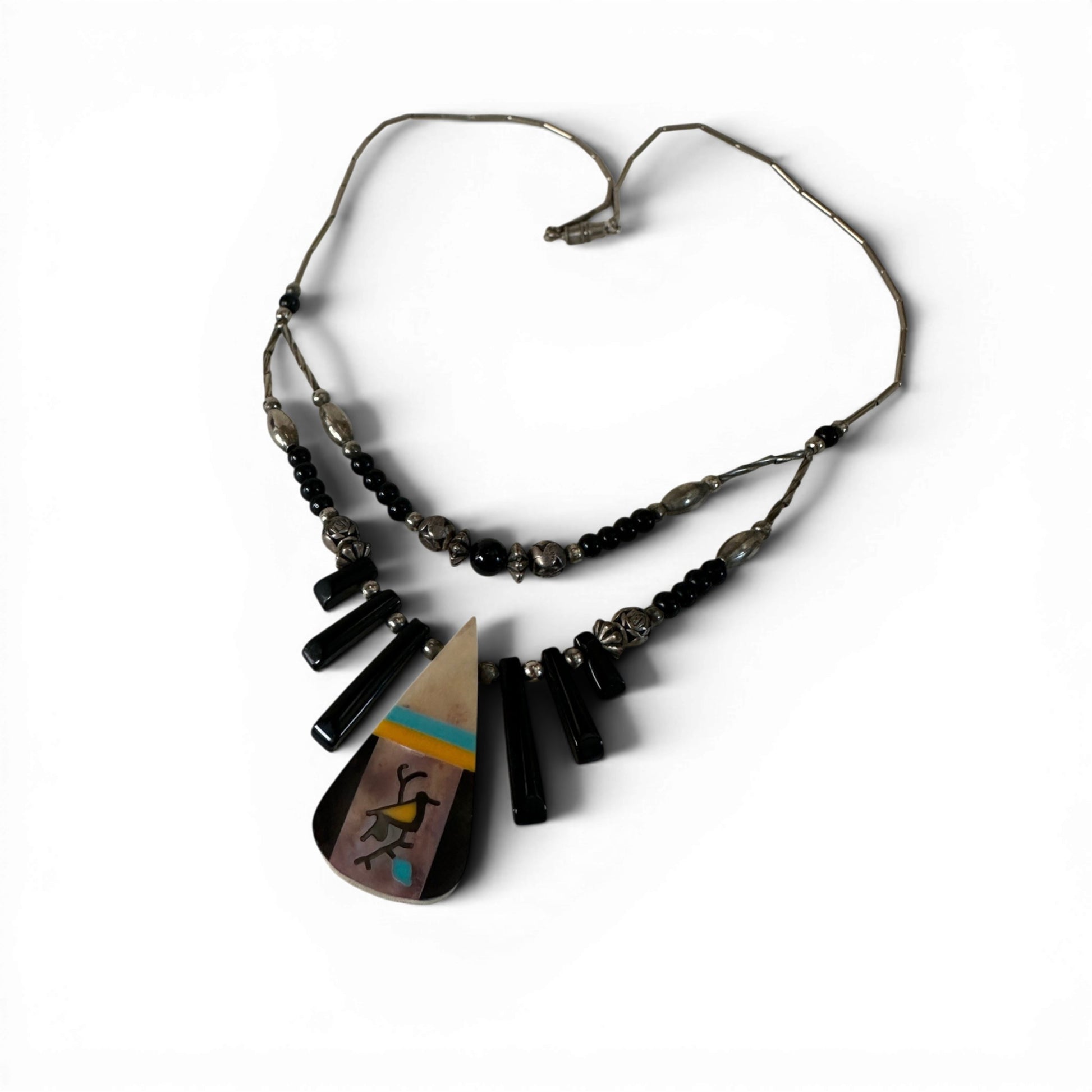 Detail of hand-stamped sterling silver beads with animal and floral motifs on double-strand necklace with black rectangula...