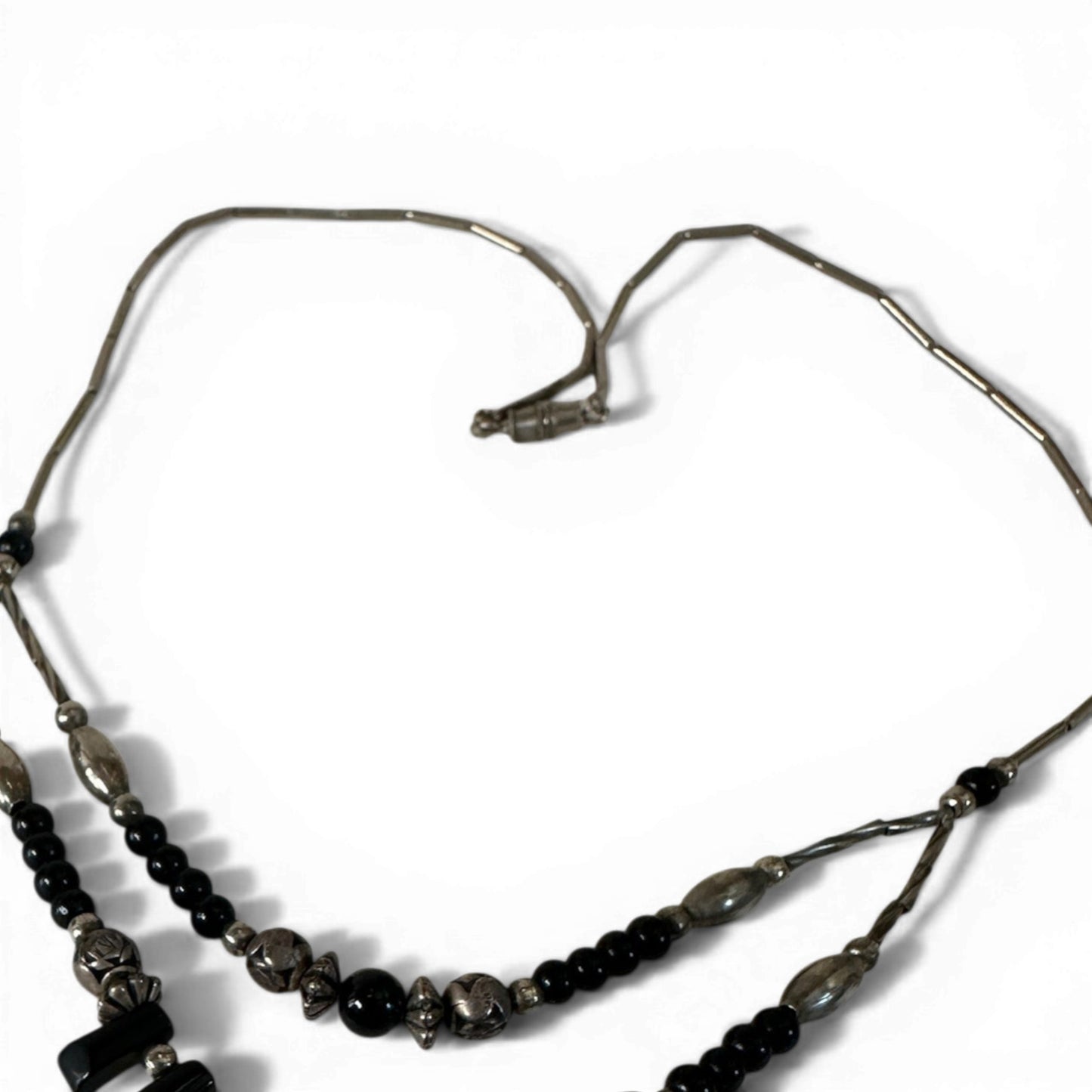 Full necklace laid flat showing barrel clasp, elongated tube bead strands, and flanking black drop elements with central i...
