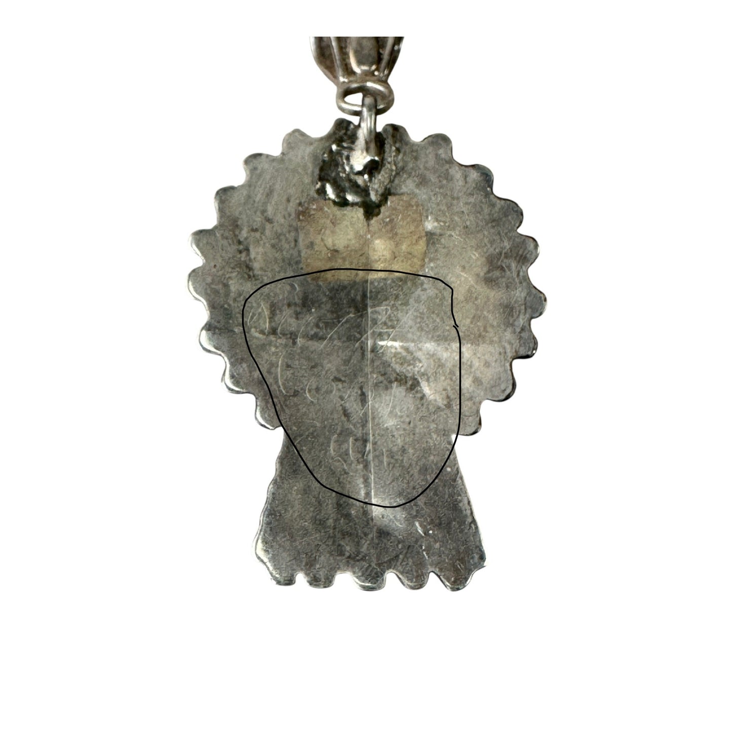 Flat silver back plate of kachina pendant showing scalloped edge, ornate multi-finger bail, and cursive artist hallmark in...