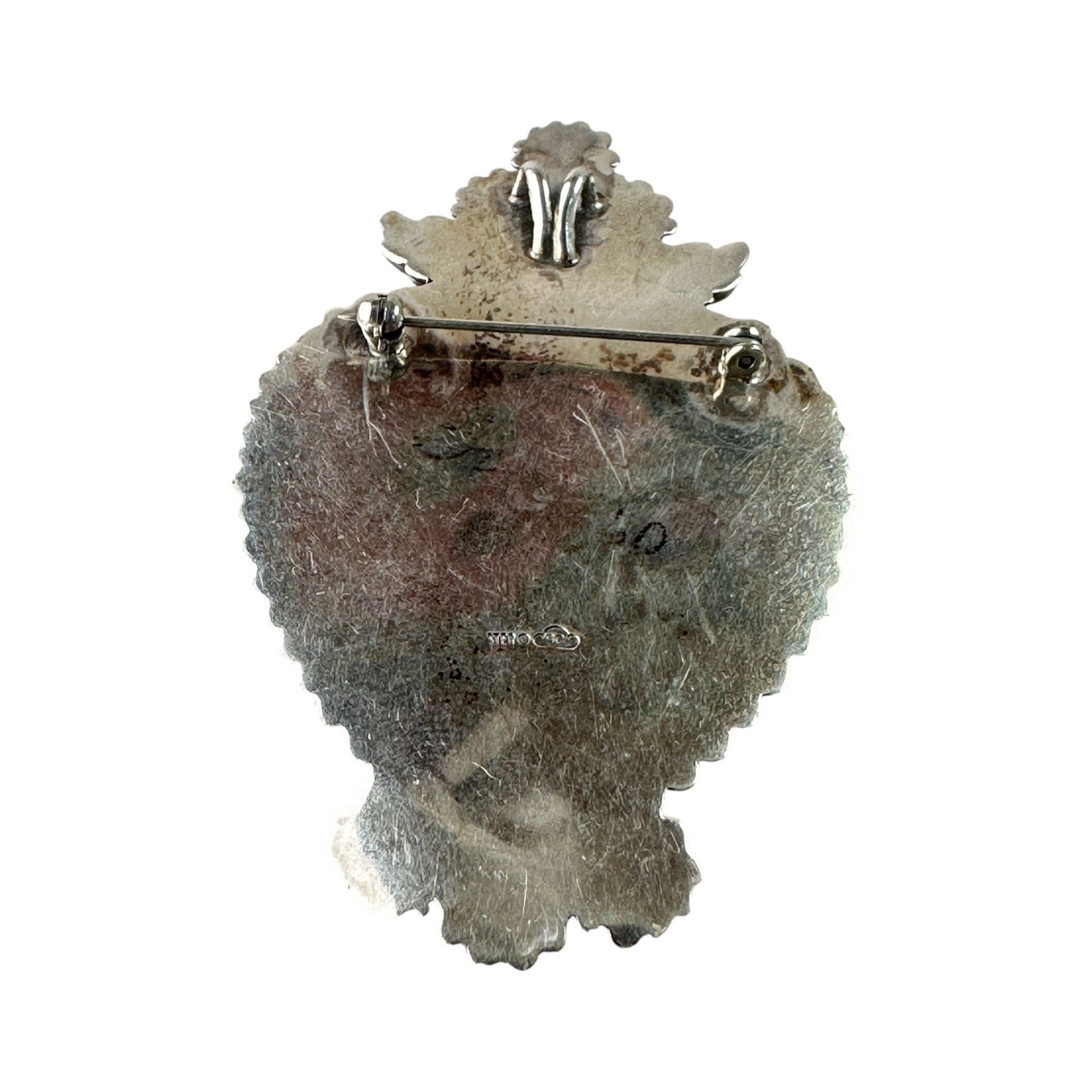 Reverse of heart brooch showing flat sterling silver backing, pin-stem roller catch clasp, and partially legible maker's h...
