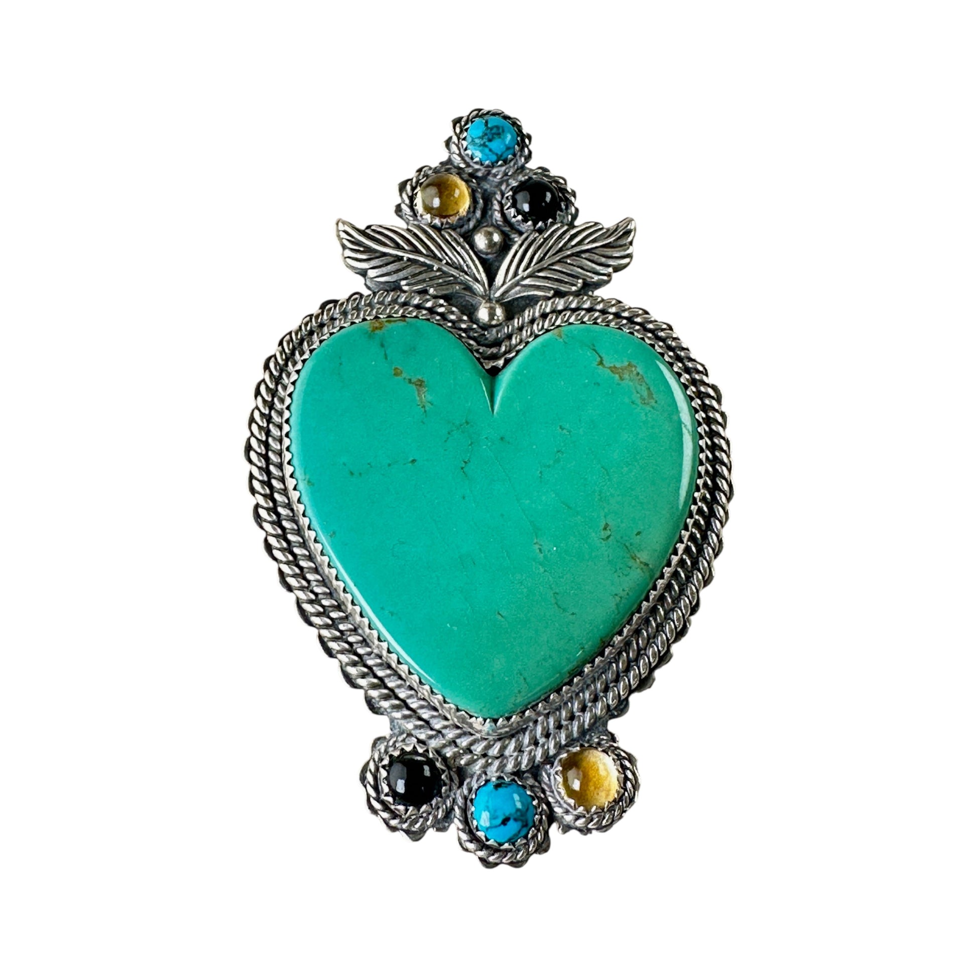Close-up of crown cluster on heart brooch showing three individually bezelled cabochons — turquoise, tiger's eye, and onyx...