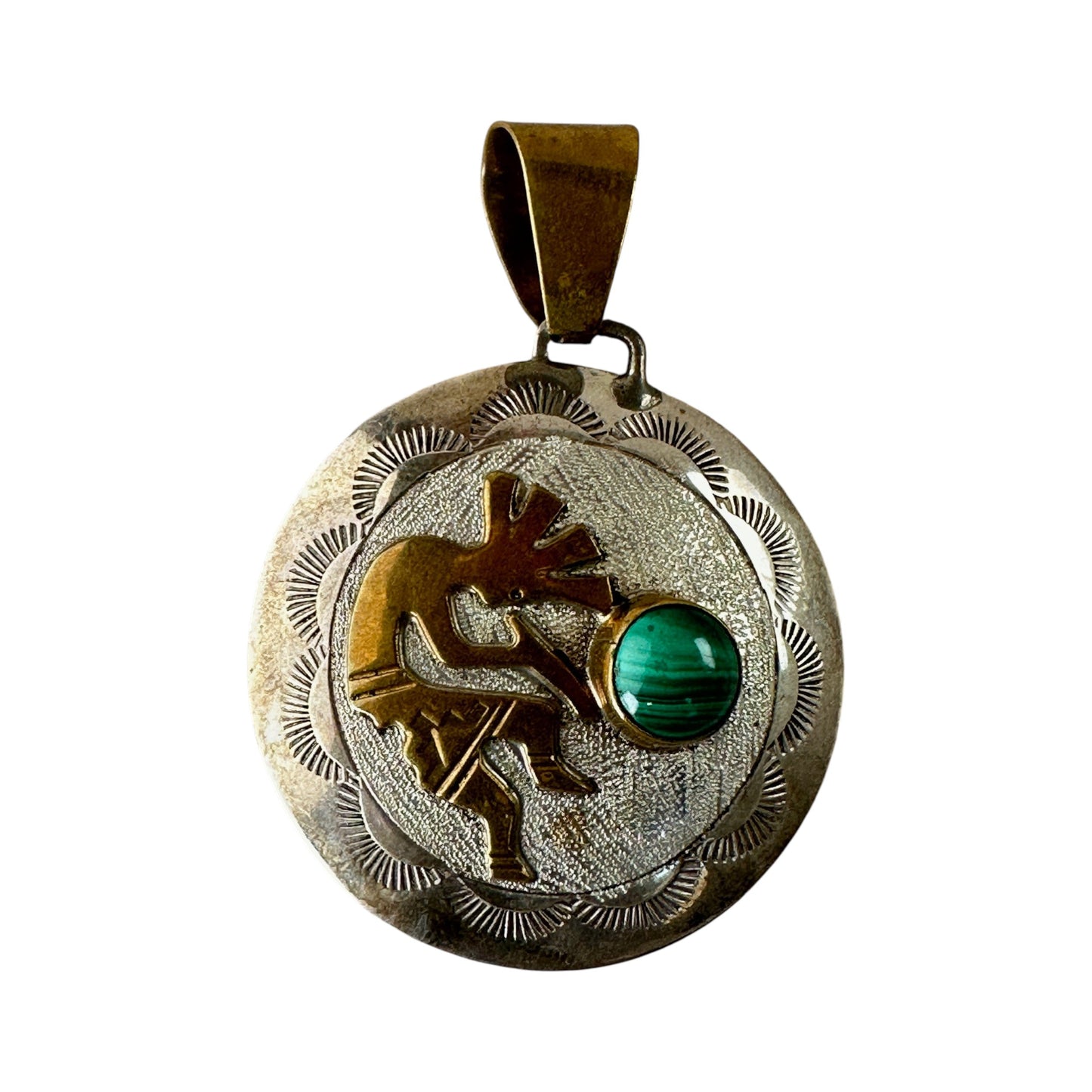 Close-up of incised radial stamp work on sterling silver disc border and gold-filled Kokopelli figure with malachite cabochon