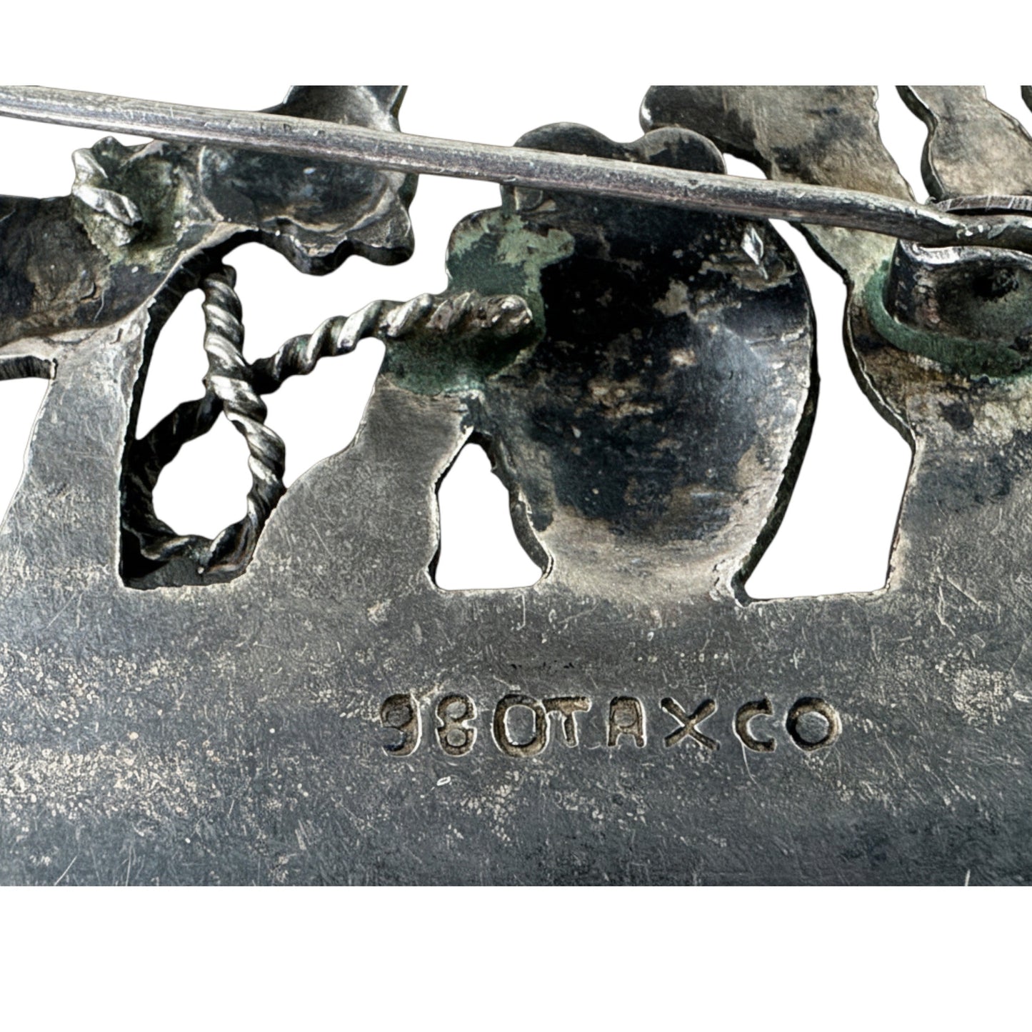 Close-up of stamped 980 TAXCO hallmark on front base panel of silver scenic silhouette brooch with dark oxidized finish