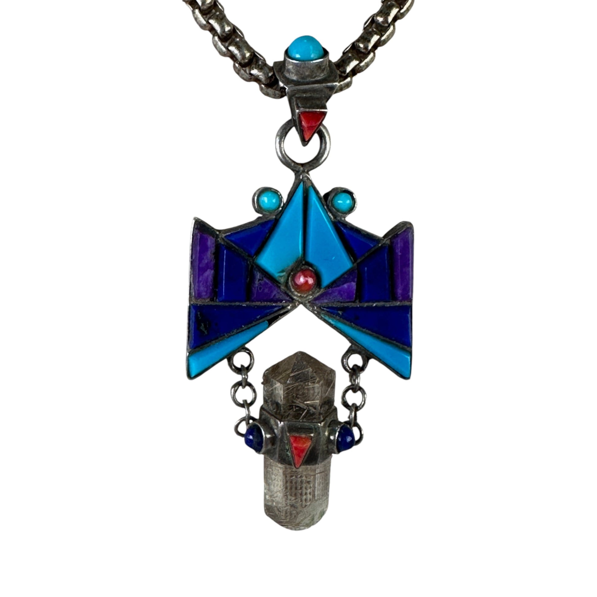 Close-up of geometric thunderbird medallion showing channel-inlay stone tiles in turquoise, lapis lazuli, sugilite, and co...