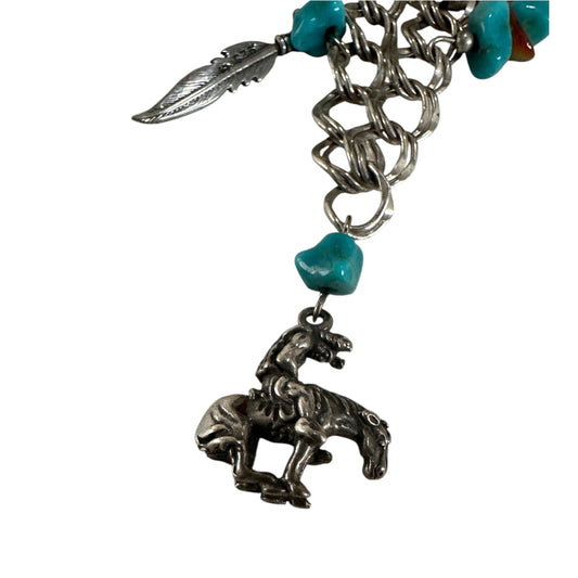 Sterling silver Southwestern charm necklace by ST showing rearing horse, bull skull, cactus, and feather charms with orang...