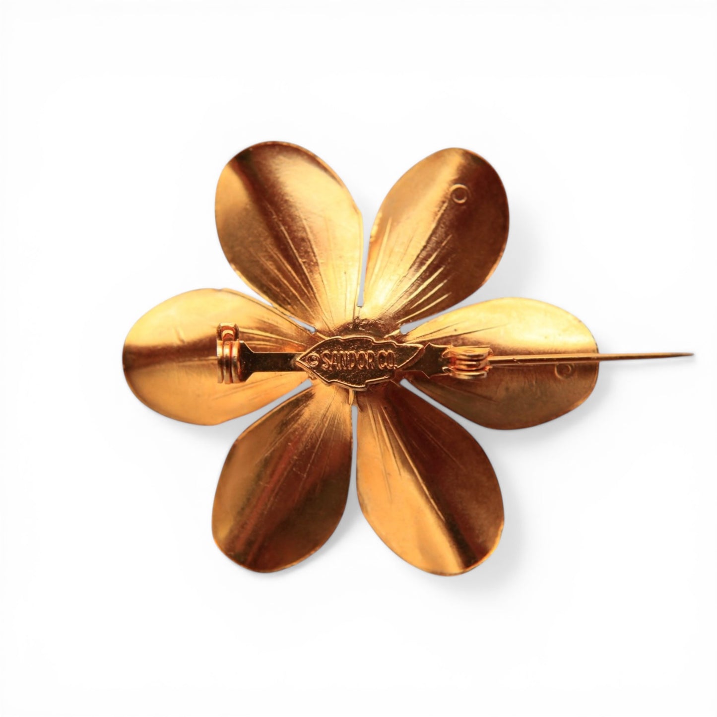 Reverse of Sandor Co. signed enamel flower brooch showing stamped gold-tone back, C-clasp pin stem, and maker's cartouche tag