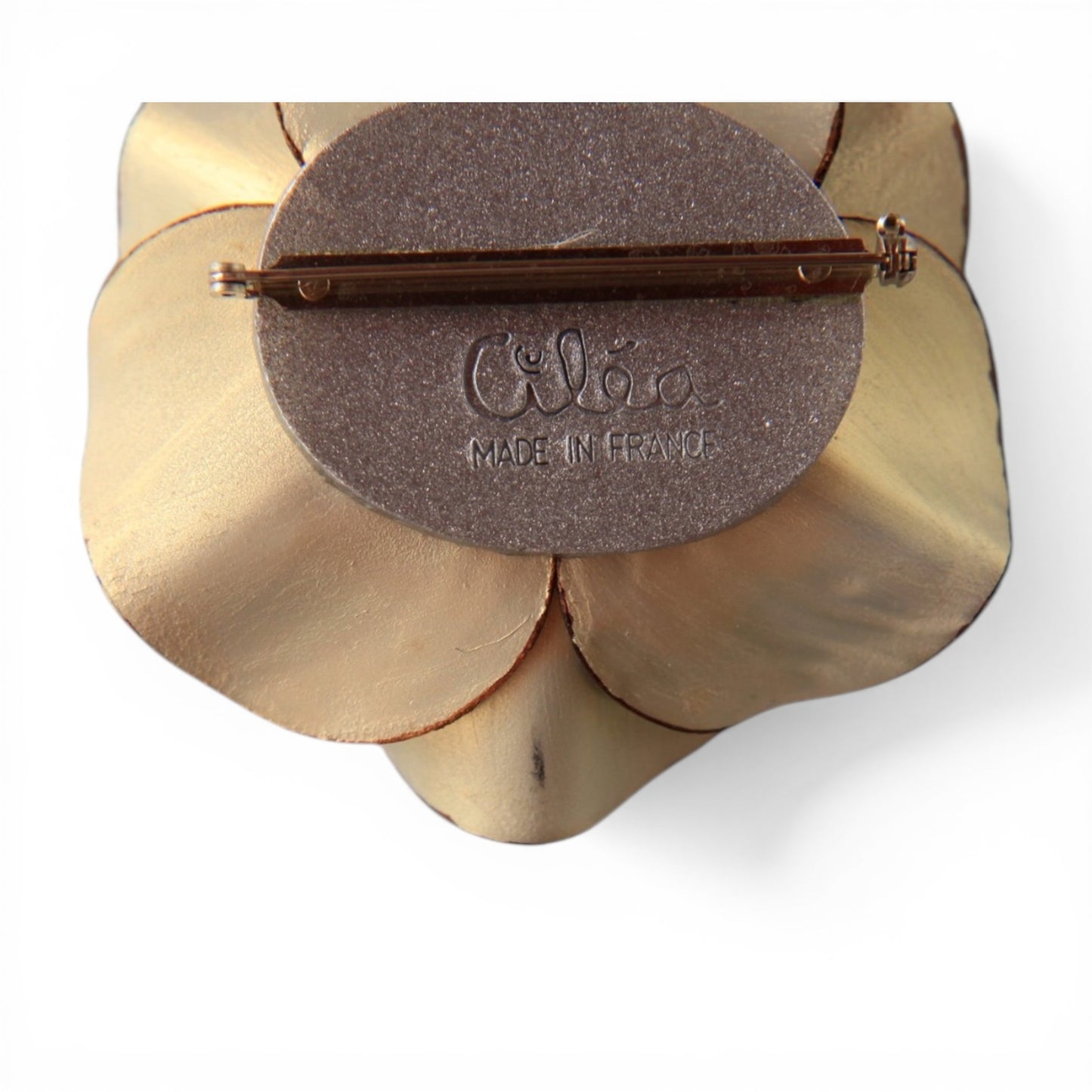 Reverse of Cilea floral brooch showing gold-tone petal backs, brown oval disc with embossed Cilea signature and bar pin fa...