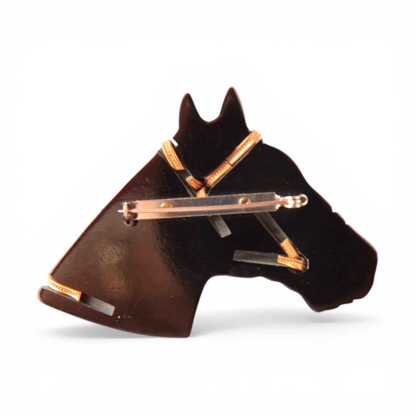 Reverse of carved black horse head brooch showing central bar pin clasp with rollover safety catch and flat gold-toned bri...