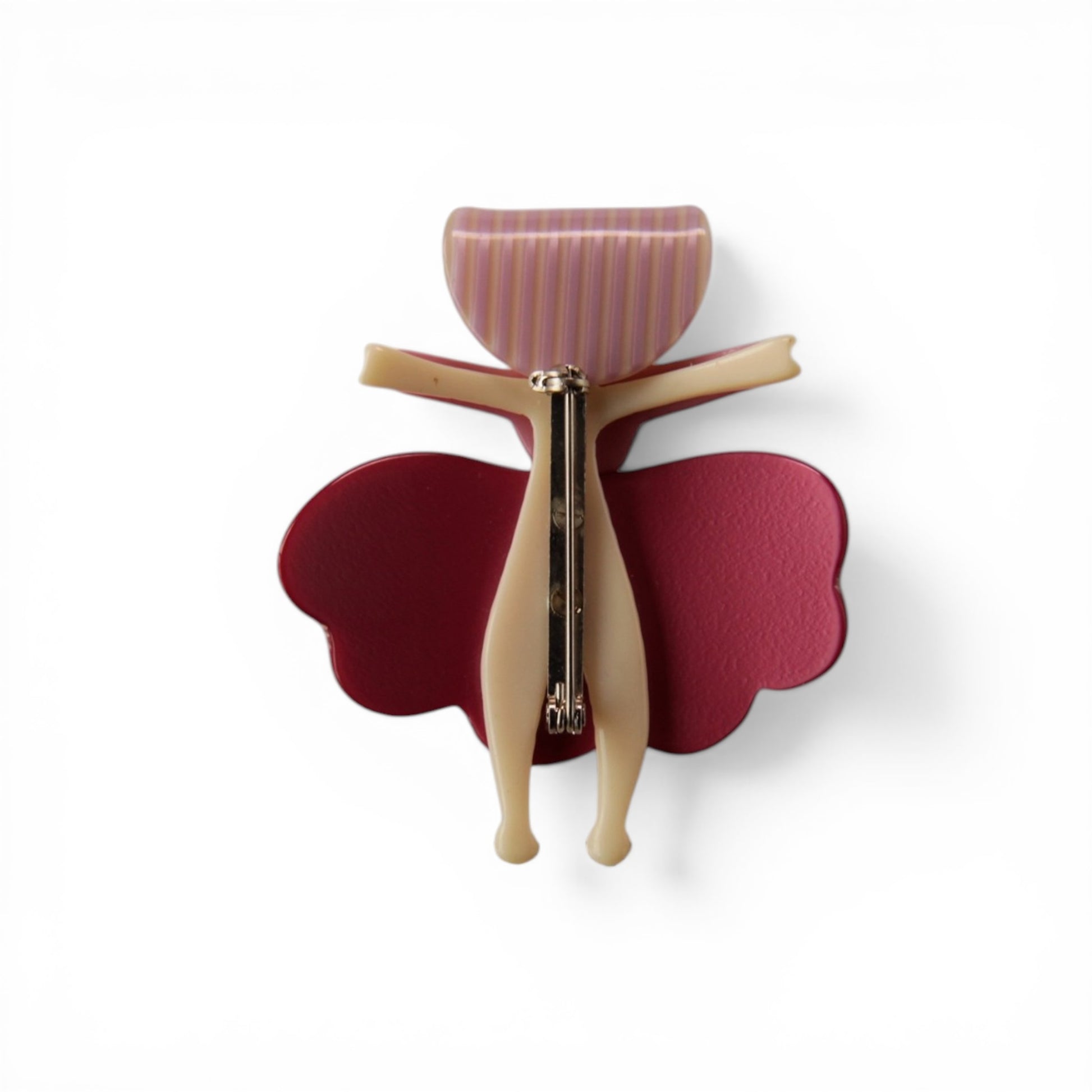 Rear view of figural plastic doll clip showing gold-tone spring-loaded claw mechanism with teeth through center of figure