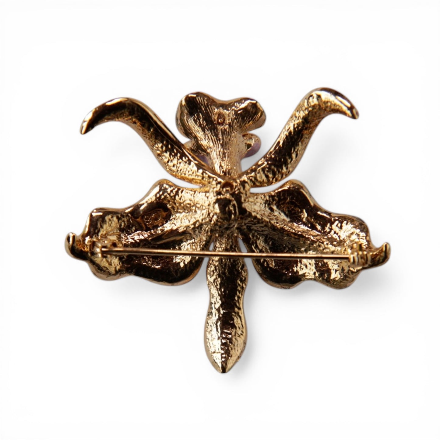 Reverse of gold-tone orchid brooch showing textured cast metal backing and standard roll-over C-catch pin stem mechanism