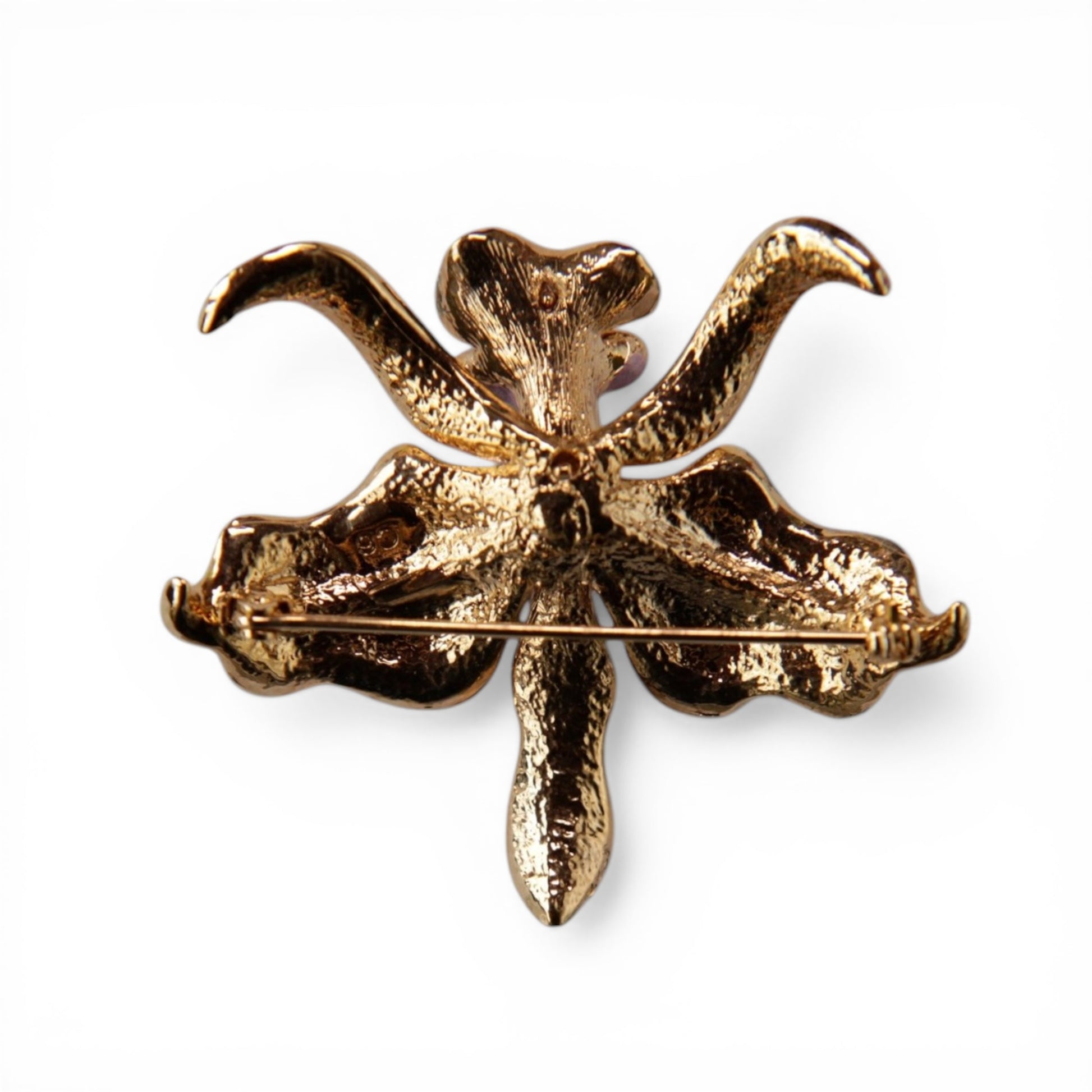 Reverse of gold-tone orchid brooch showing textured cast metal backing and standard roll-over C-catch pin stem mechanism