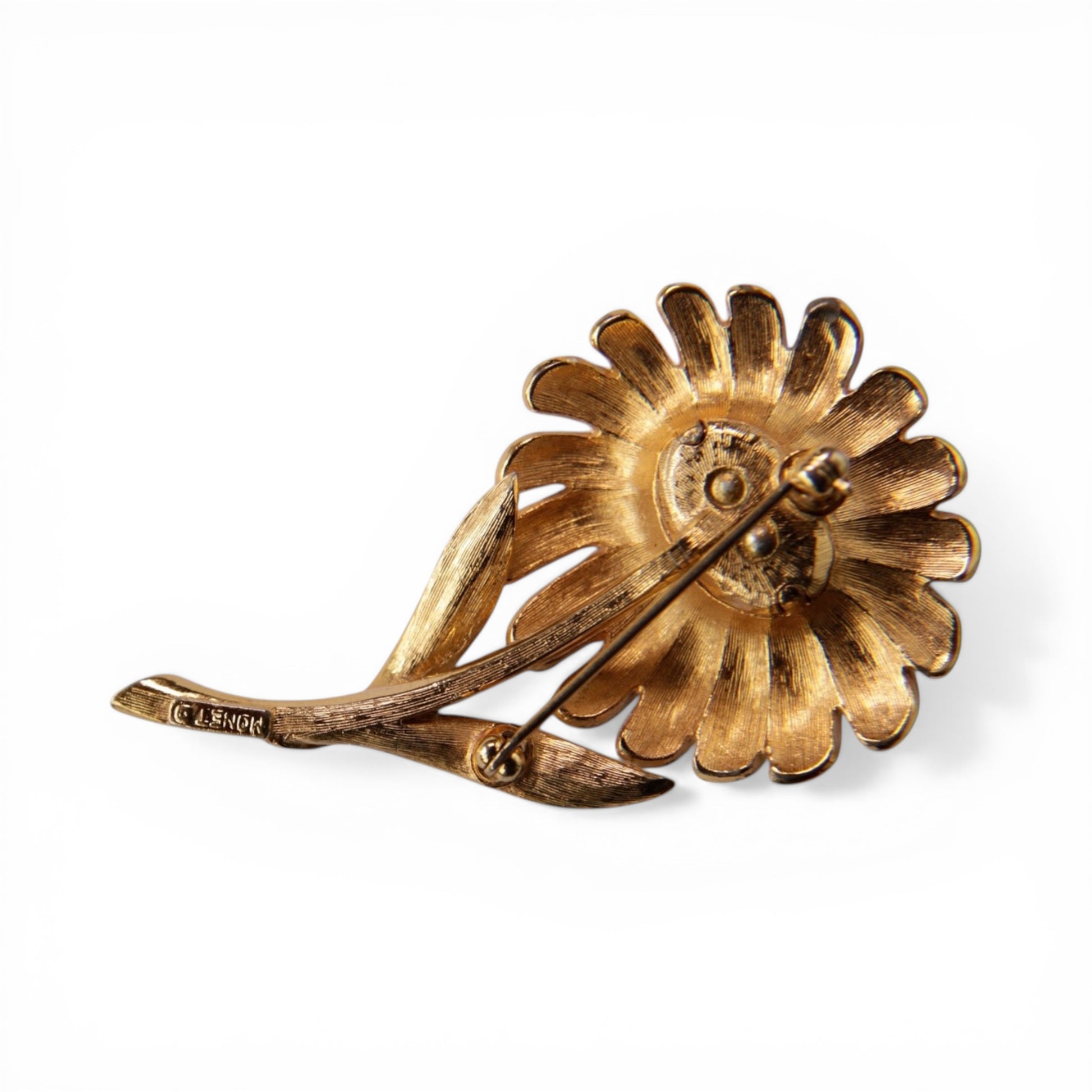 Reverse of MONET daisy brooch showing gold-tone cast metal back, roll-over safety clasp, and stamped MONET mark on stem