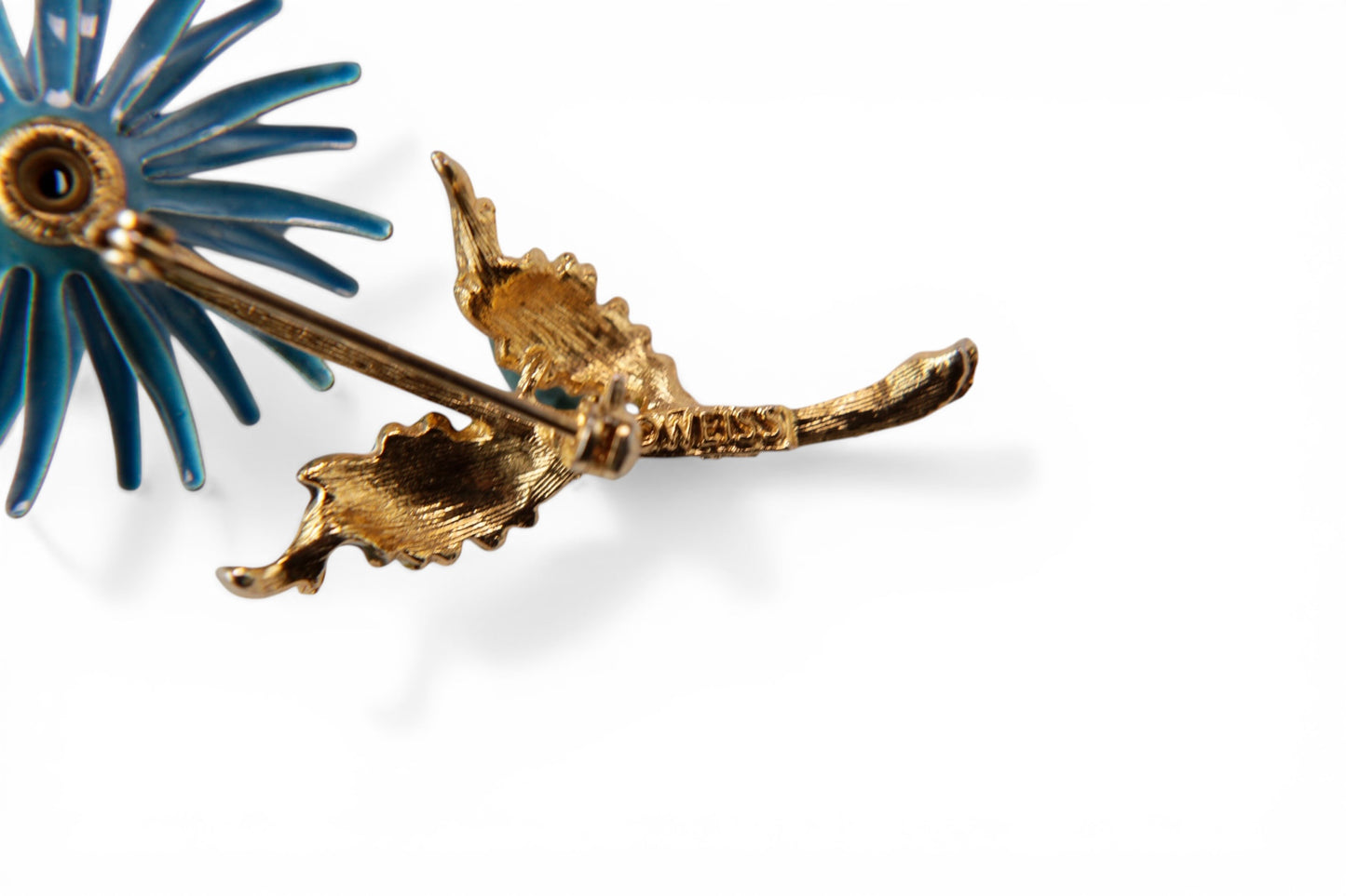 Reverse of blue enamel flower brooch showing WEISS maker's mark stamped on gold-tone stem with roller clasp pin mechanism