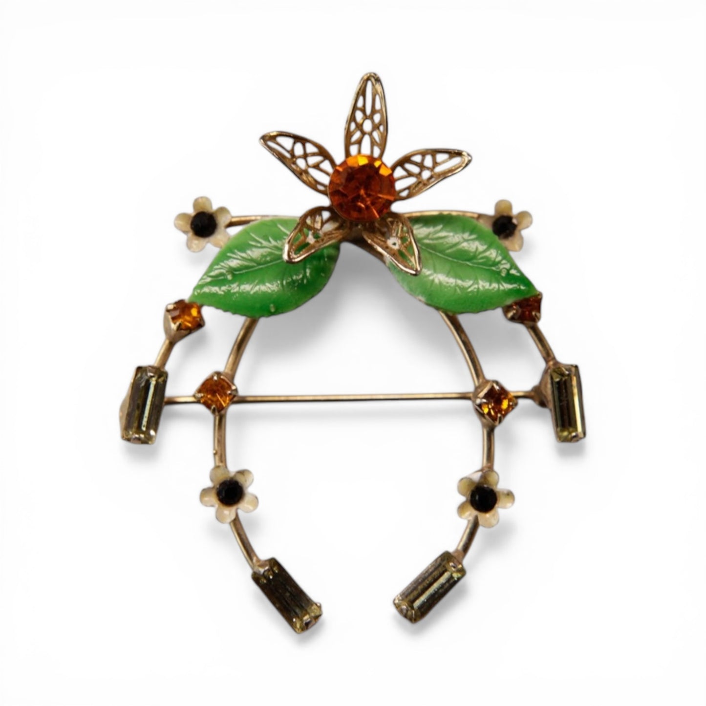 Gold-tone horseshoe brooch with cream enamel daisy flowers, amber rhinestones, and olive baguettes arranged around the arc...