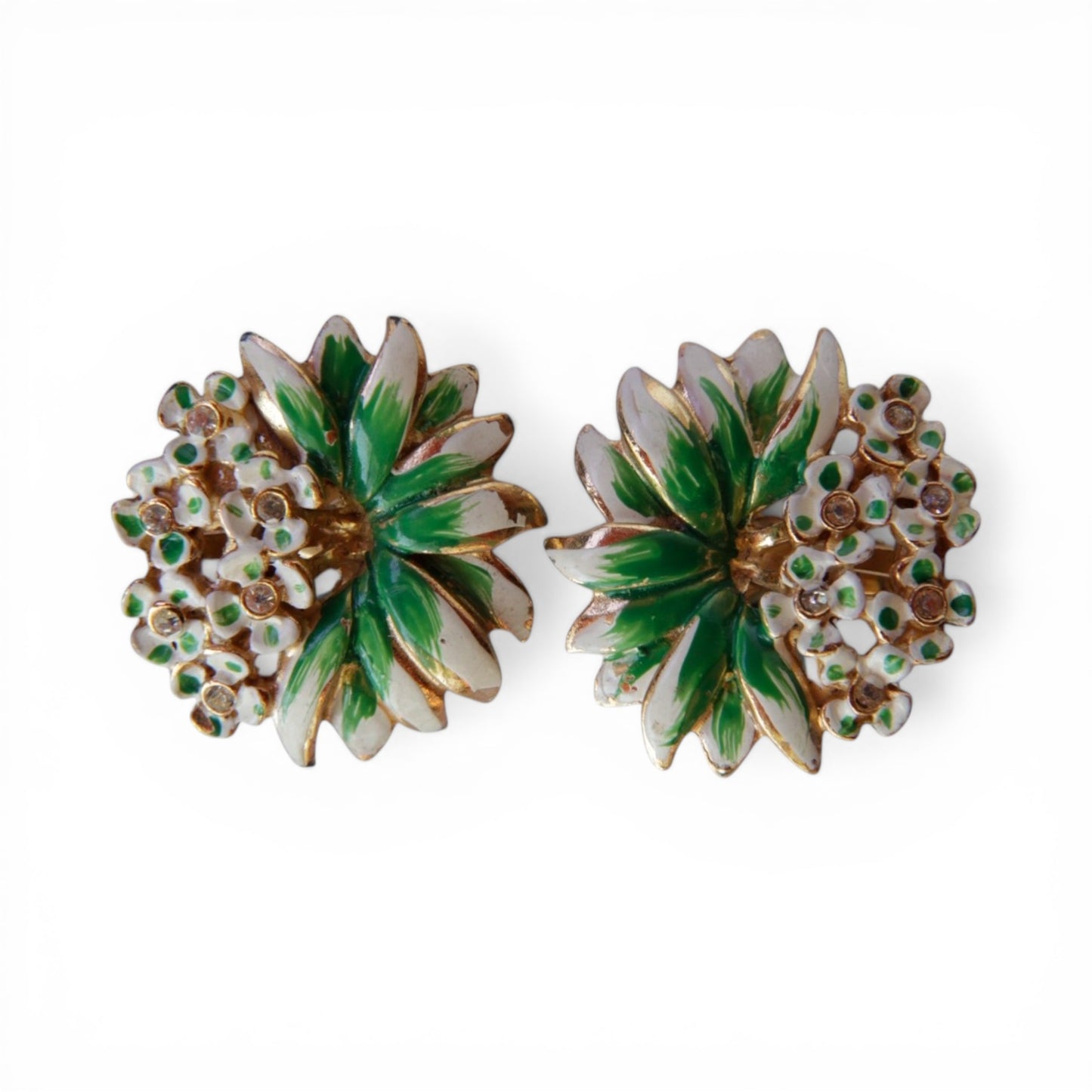 Round clip-on earrings with green and white enamel starburst center, surrounded by white enamel flowers with clear rhinest...