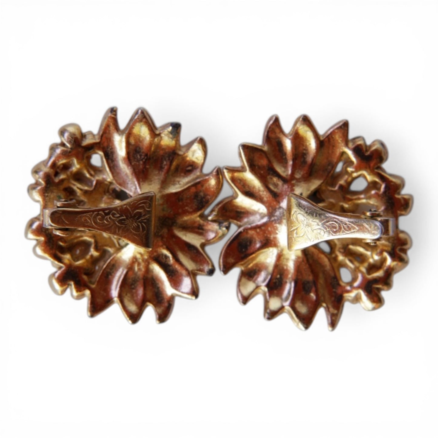 Reverse of round clip-on earrings showing engraved gold-tone folded paddle-style clip findings with patina and oxidation o...