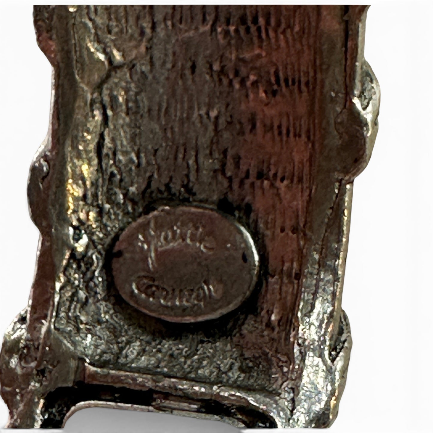 Side profile of wide silver-tone hinged bangle showing screw-pin barrel hinge and raised surface relief detailing