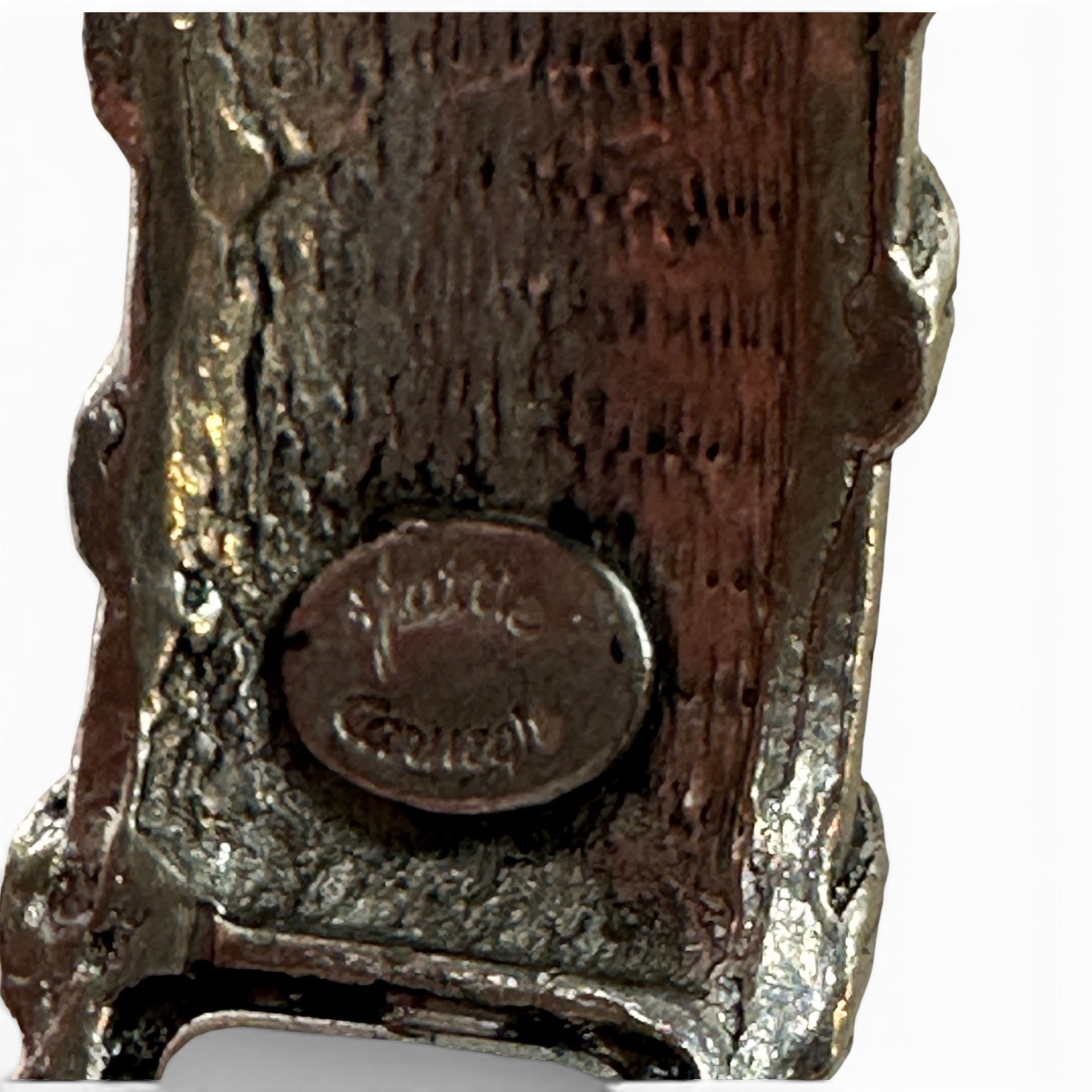 Side profile of wide silver-tone hinged bangle showing screw-pin barrel hinge and raised surface relief detailing