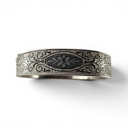 Wide sterling silver hinged bangle bracelet with niello-filled engraved floral and scrollwork decoration across outer surf...