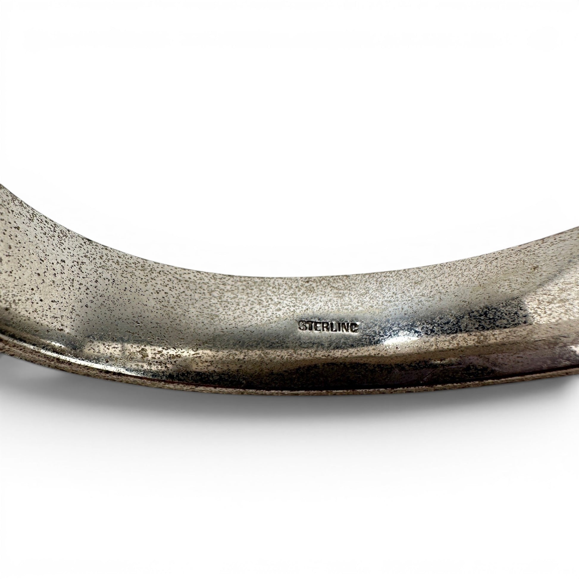 Interior of sterling silver hinged bangle showing STERLING and F.M.Co. maker's marks stamped on smooth hollow-form inner s...