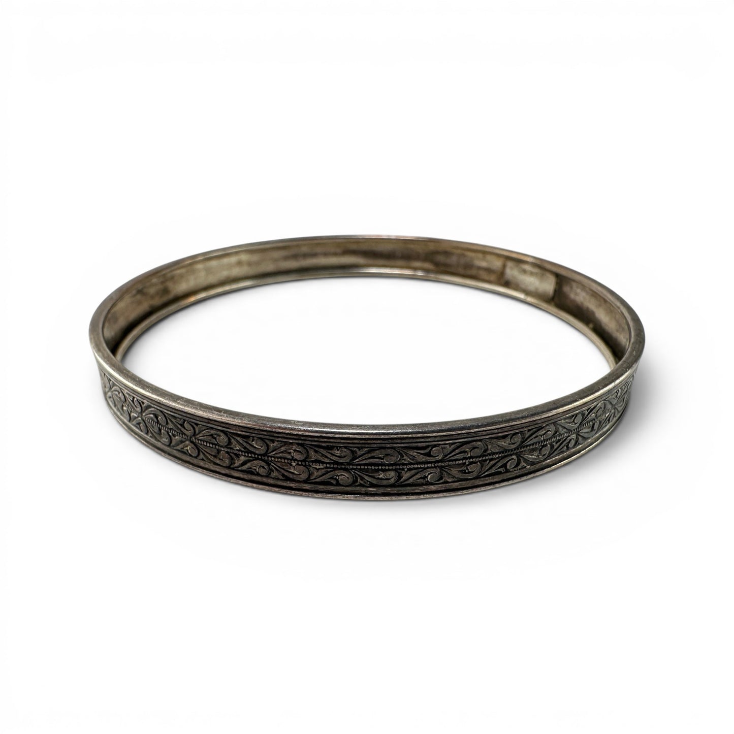Hinged sterling silver bangle by Coro with continuous scrolling foliate engraving on flat outer face, oxidized finish