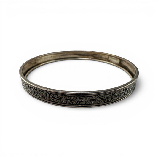 Hinged sterling silver bangle by Coro with continuous scrolling foliate engraving on flat outer face, oxidized finish