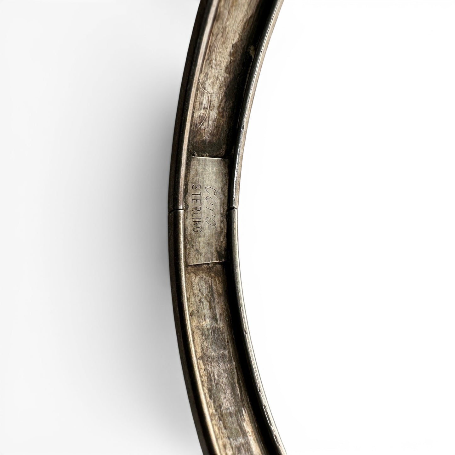 Side view of Coro hinged sterling silver bangle showing clasp mechanism, flat profile, and darkened engraving recesses