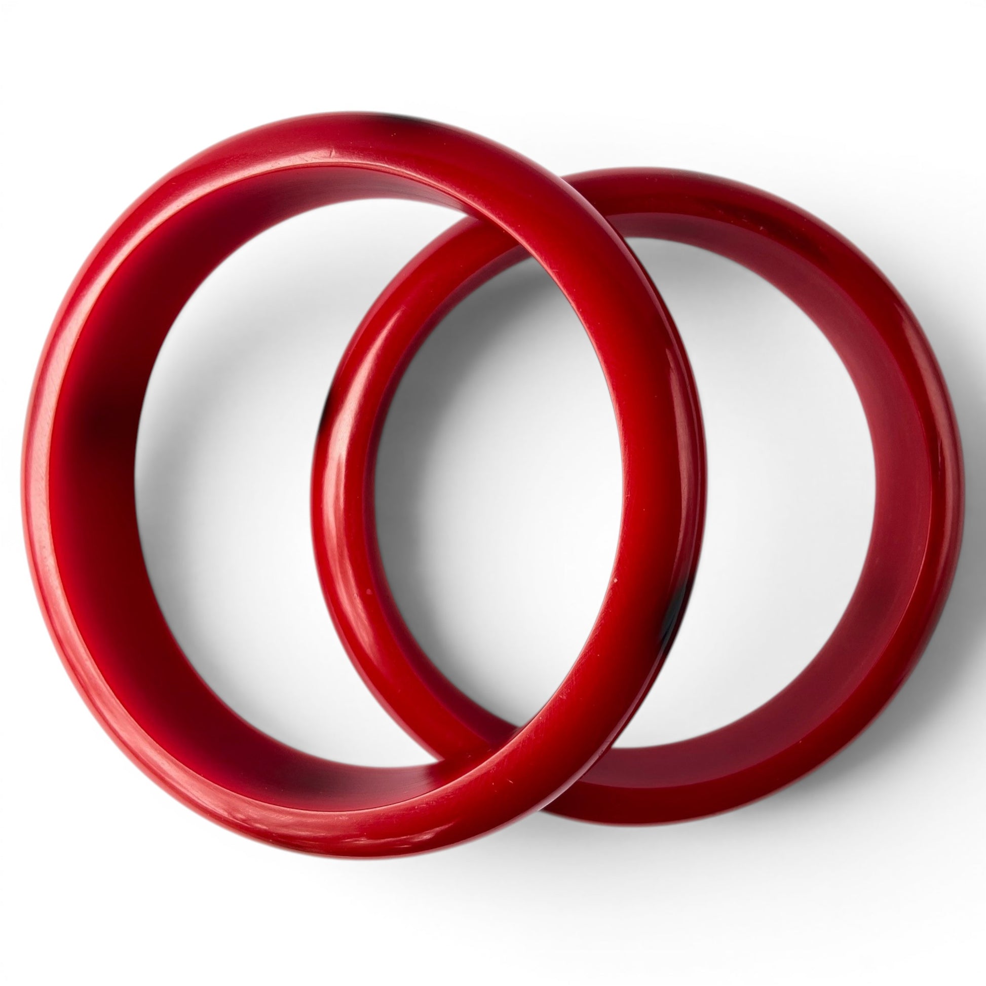 Close-up of dotted cherry red Bakelite bangle showing flush-inlaid dark oval dot inlays spaced around the full circumference