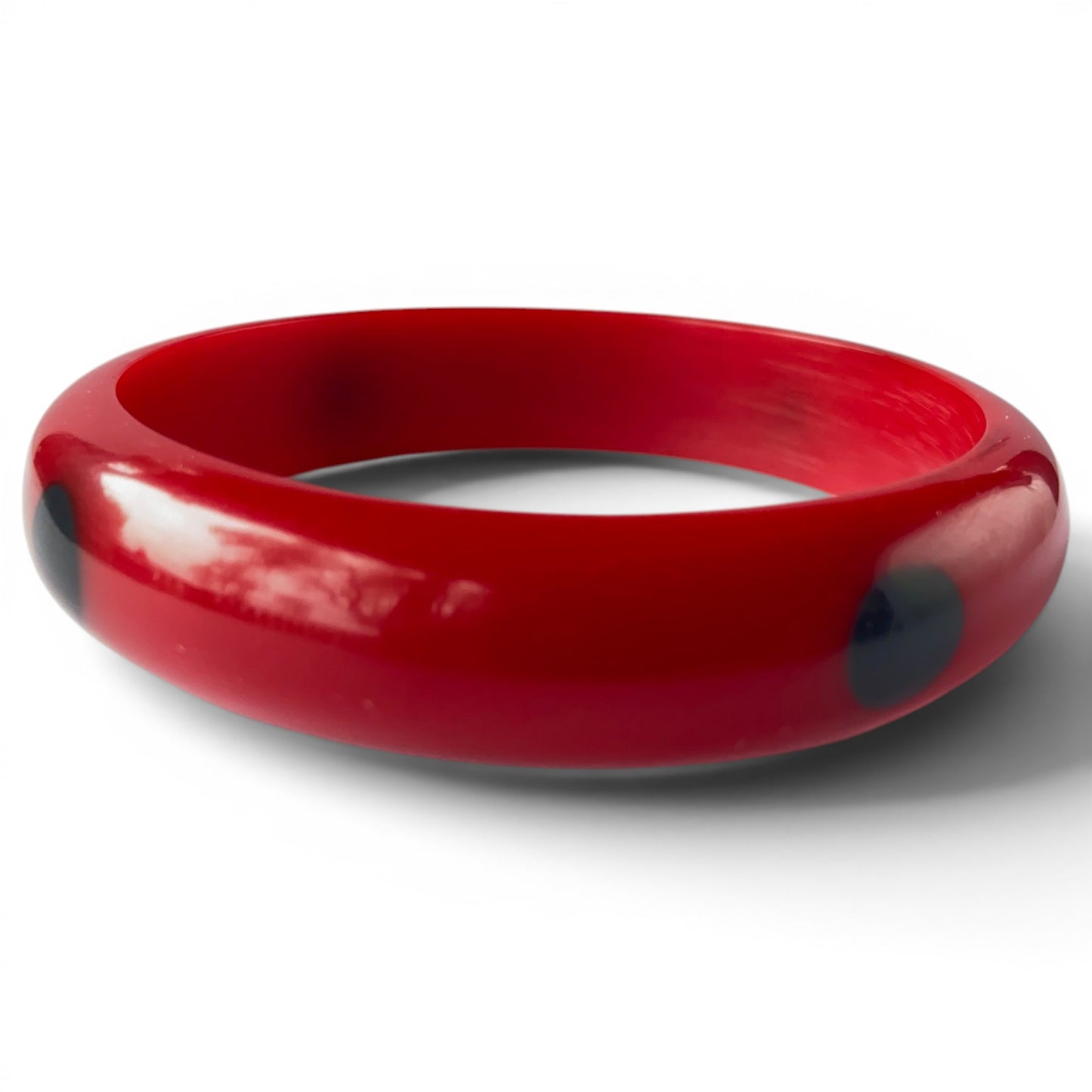 Side view of both cherry red Bakelite bangles showing rounded domed cross-section and high gloss surface with subtle red m...
