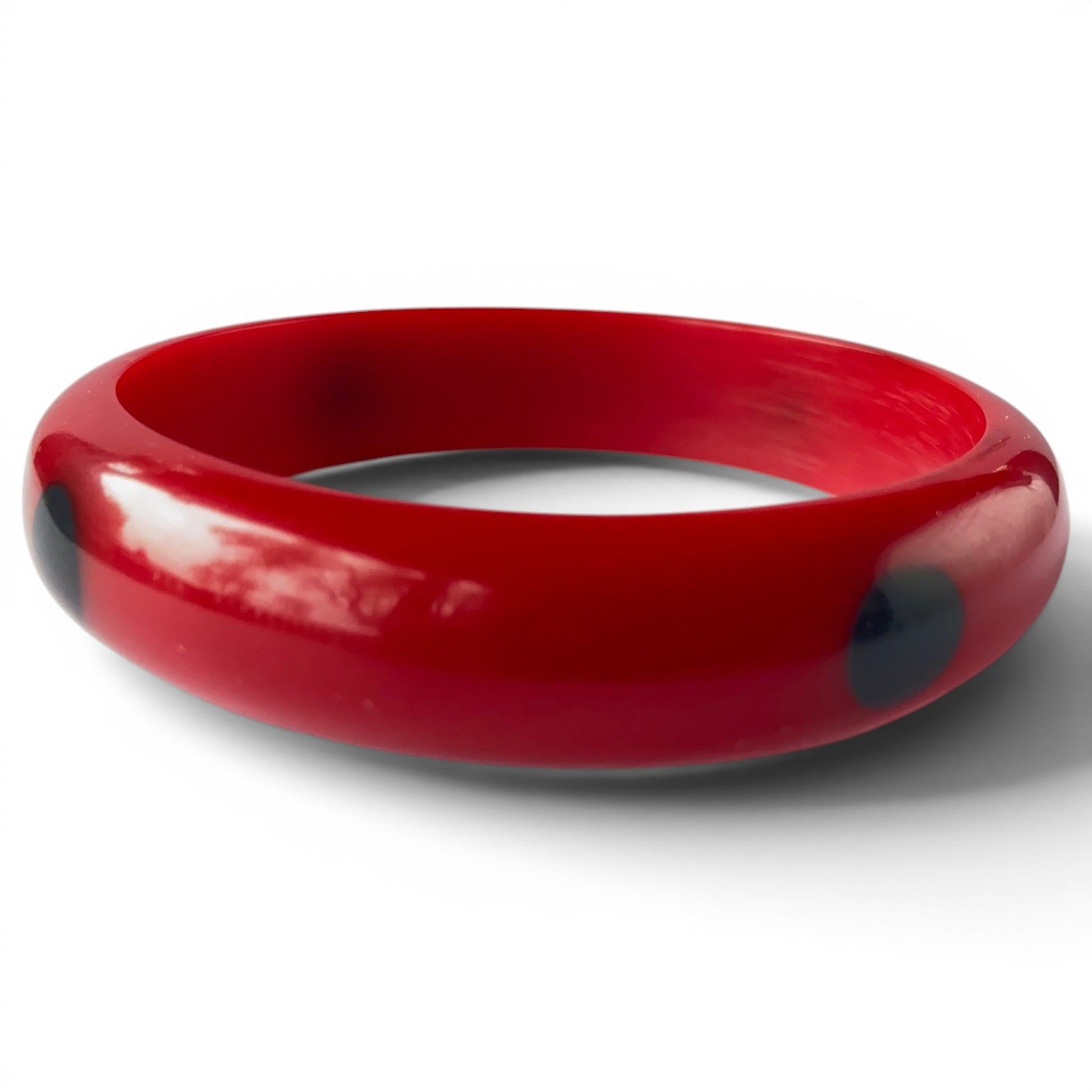 Side view of both cherry red Bakelite bangles showing rounded domed cross-section and high gloss surface with subtle red m...