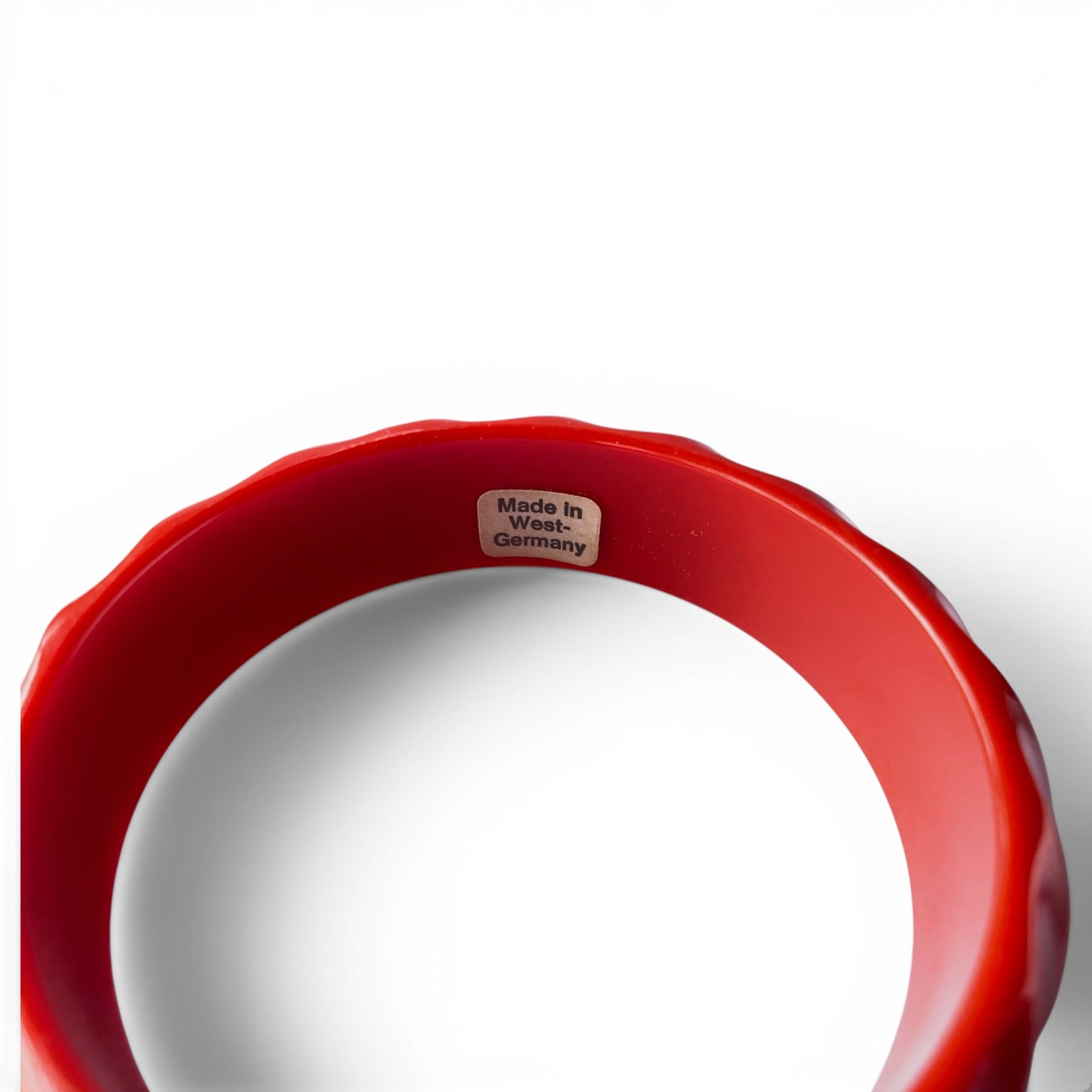 Side profile of chunky solid red Bakelite bangle showing depth of carved diagonal twist grooves and glossy surface condition
