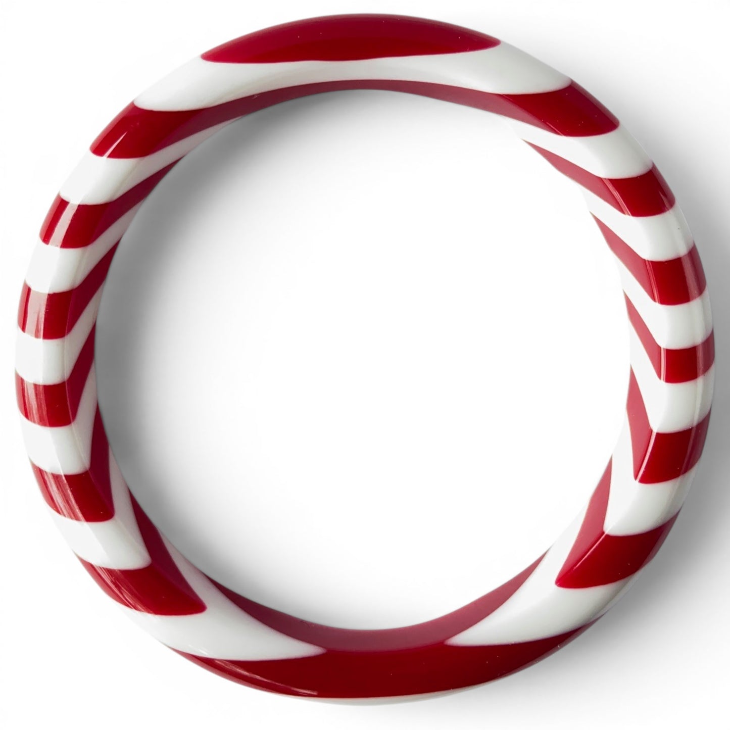 Close-up of red and white spiral stripe detail on glossy tubular acrylic bangle bracelet, seamless construction, no clasp