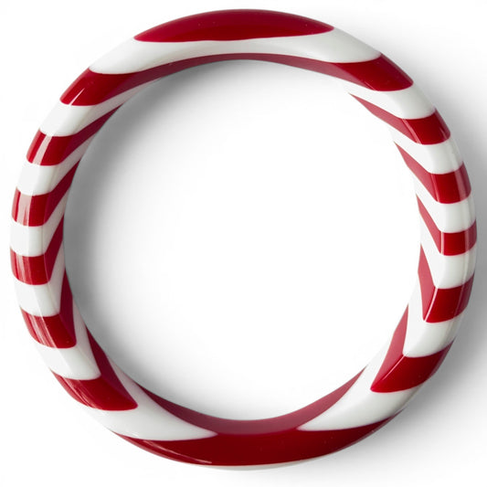 Close-up of red and white spiral stripe detail on glossy tubular acrylic bangle bracelet, seamless construction, no clasp