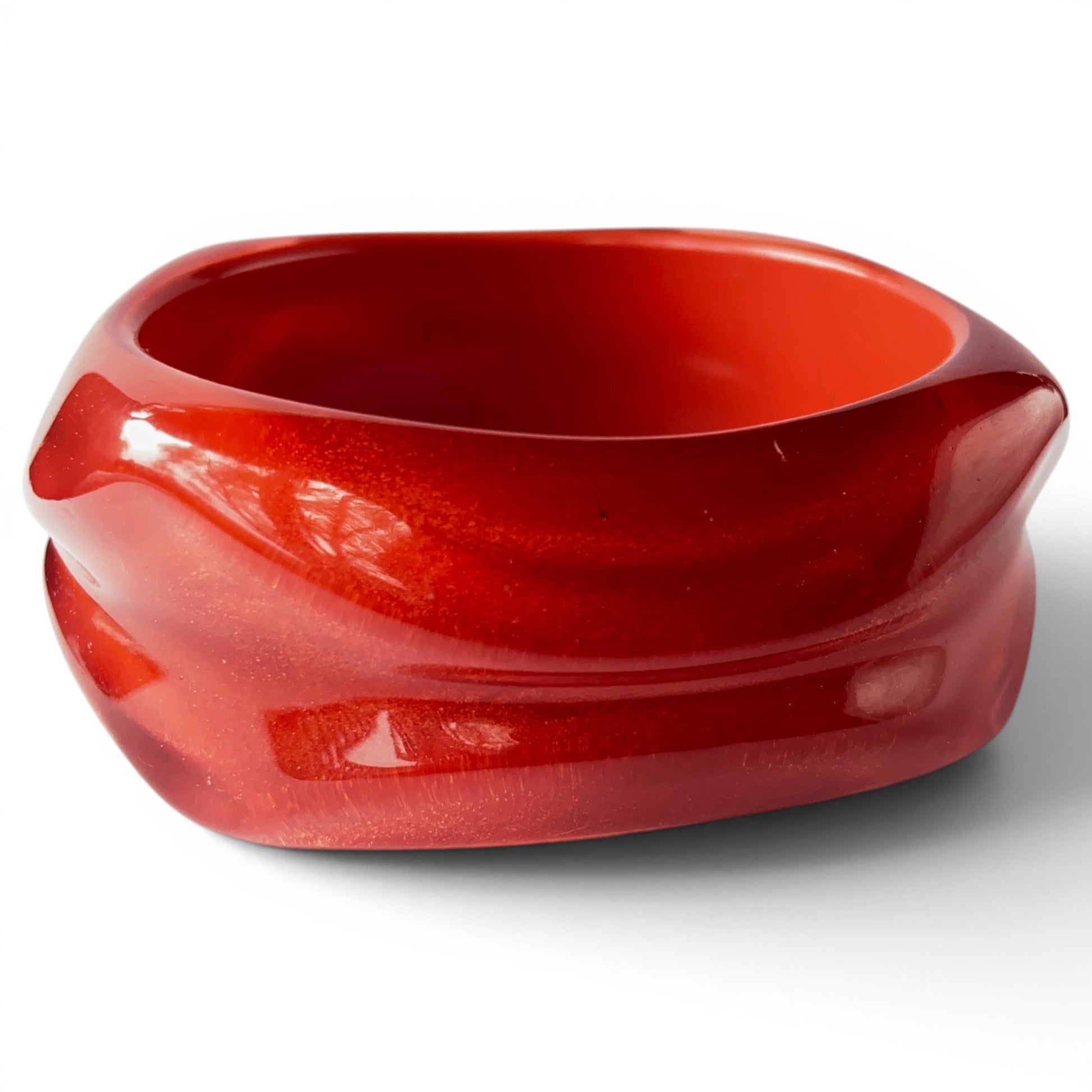 Wide chunky cherry red Bakelite bangle with carved horizontal groove and squared rounded silhouette, front view