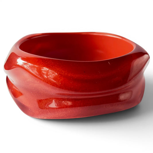 Wide chunky cherry red Bakelite bangle with carved horizontal groove and squared rounded silhouette, front view