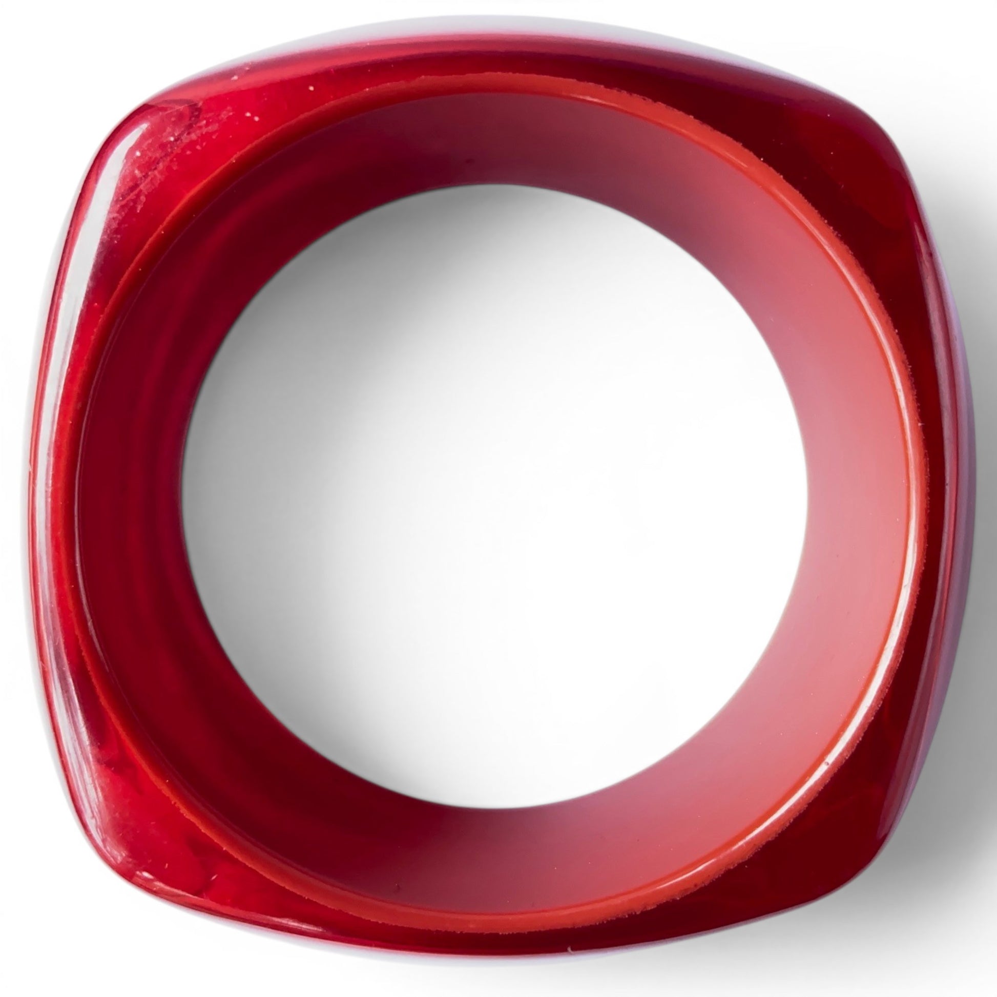 Deep translucent crimson Bakelite slip-on bangle showing two-tier carved profile and high-gloss polished exterior surface